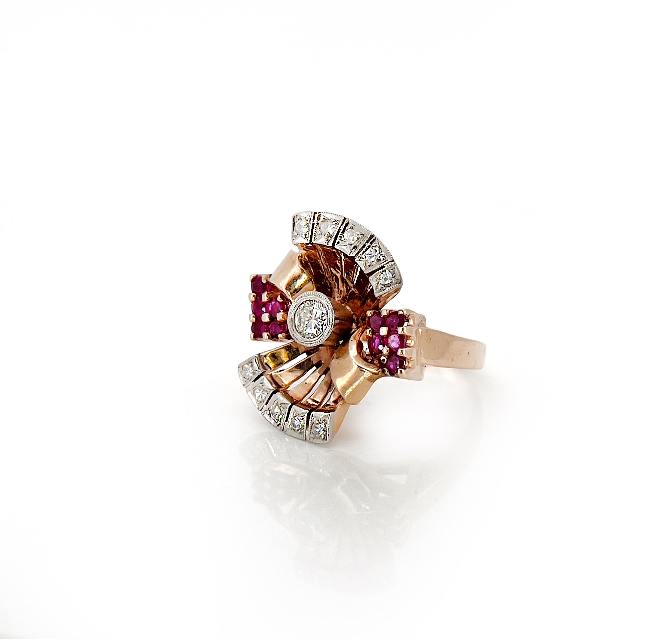 Elegant retro rose gold and palladium ring with diamonds and rubies against a white background.
