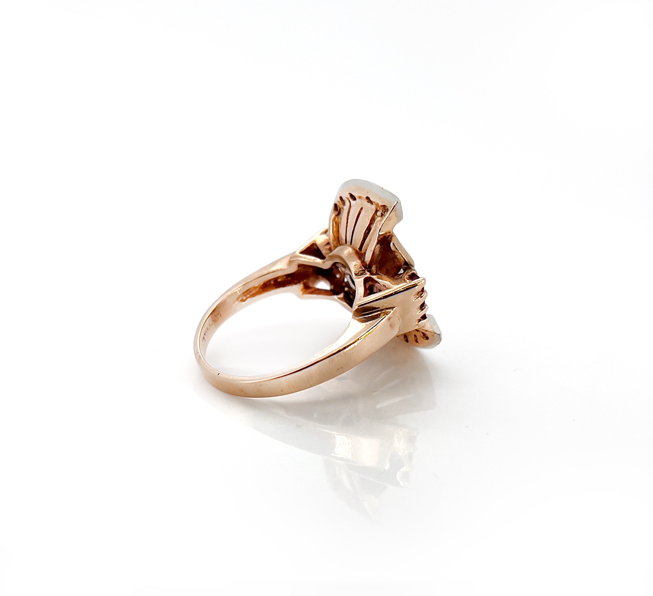 Elegant retro rose gold and palladium ring with diamonds and rubies against a white background.