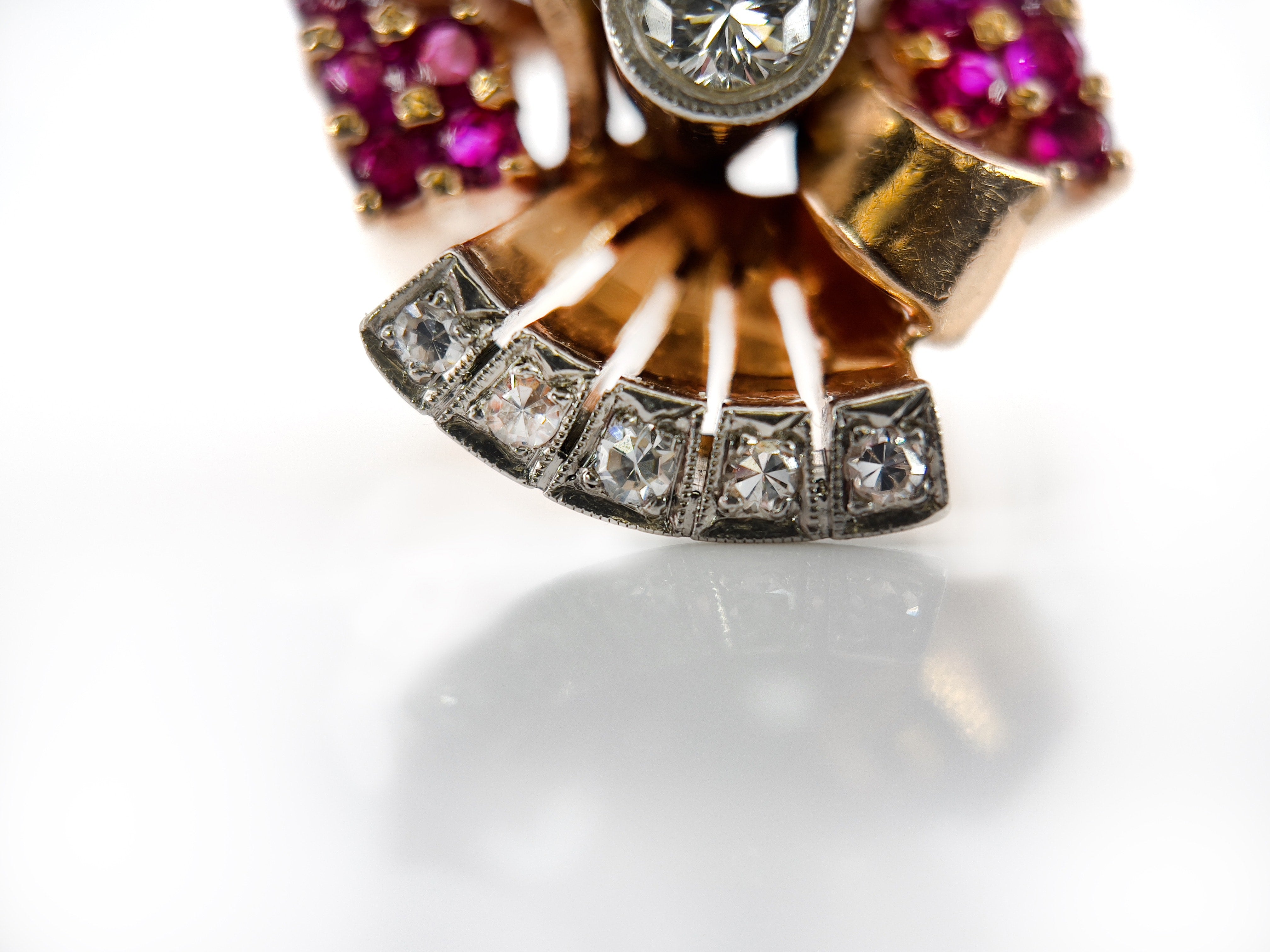 Elegant retro rose gold and palladium ring with diamonds and rubies against a white background.