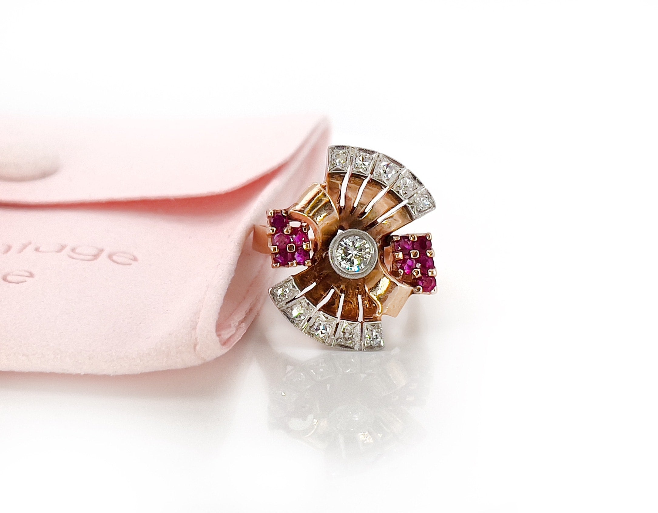 Elegant retro rose gold and palladium ring with diamonds and rubies against a white background.