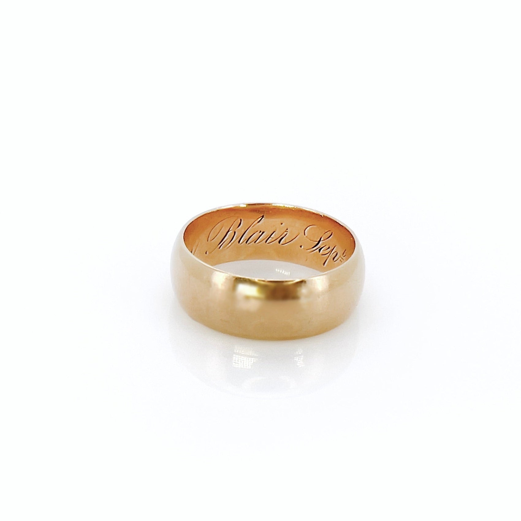 A Victorian gold band with a patina and inscription in front of a white background.