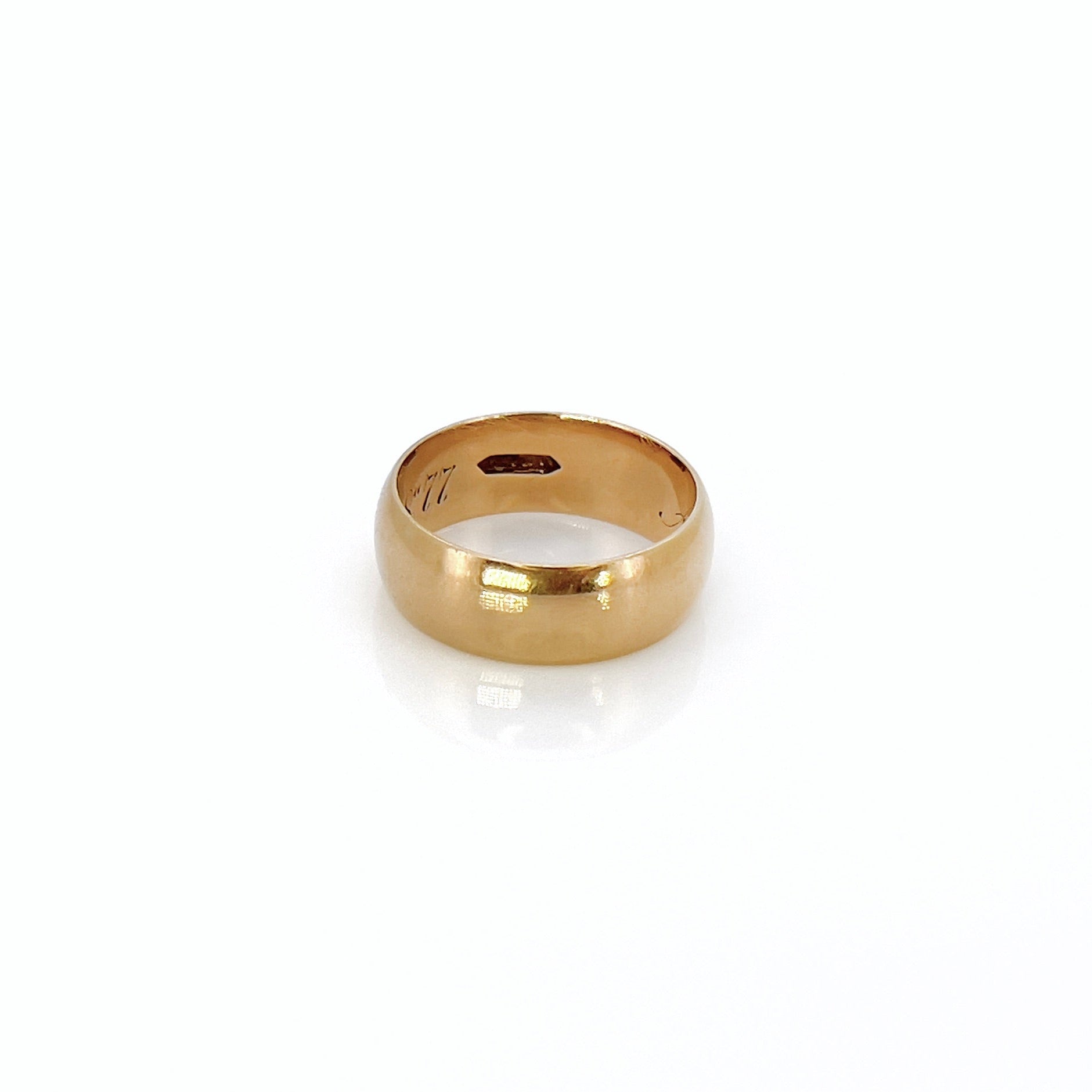 A Victorian gold band with a patina, inscription, and maker’s mark in front of a white background.