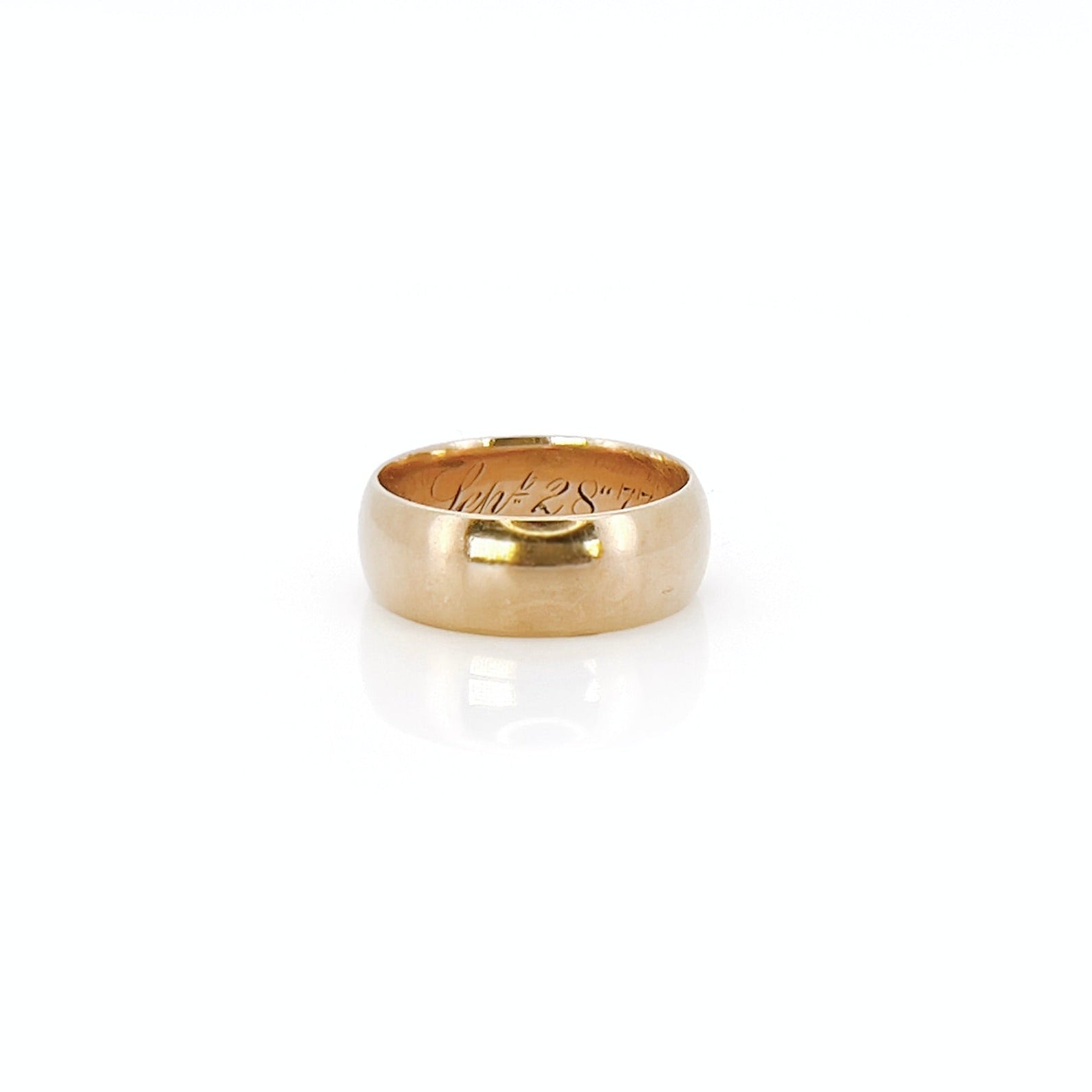 A Victorian gold band with a patina and inscription in front of a white background.