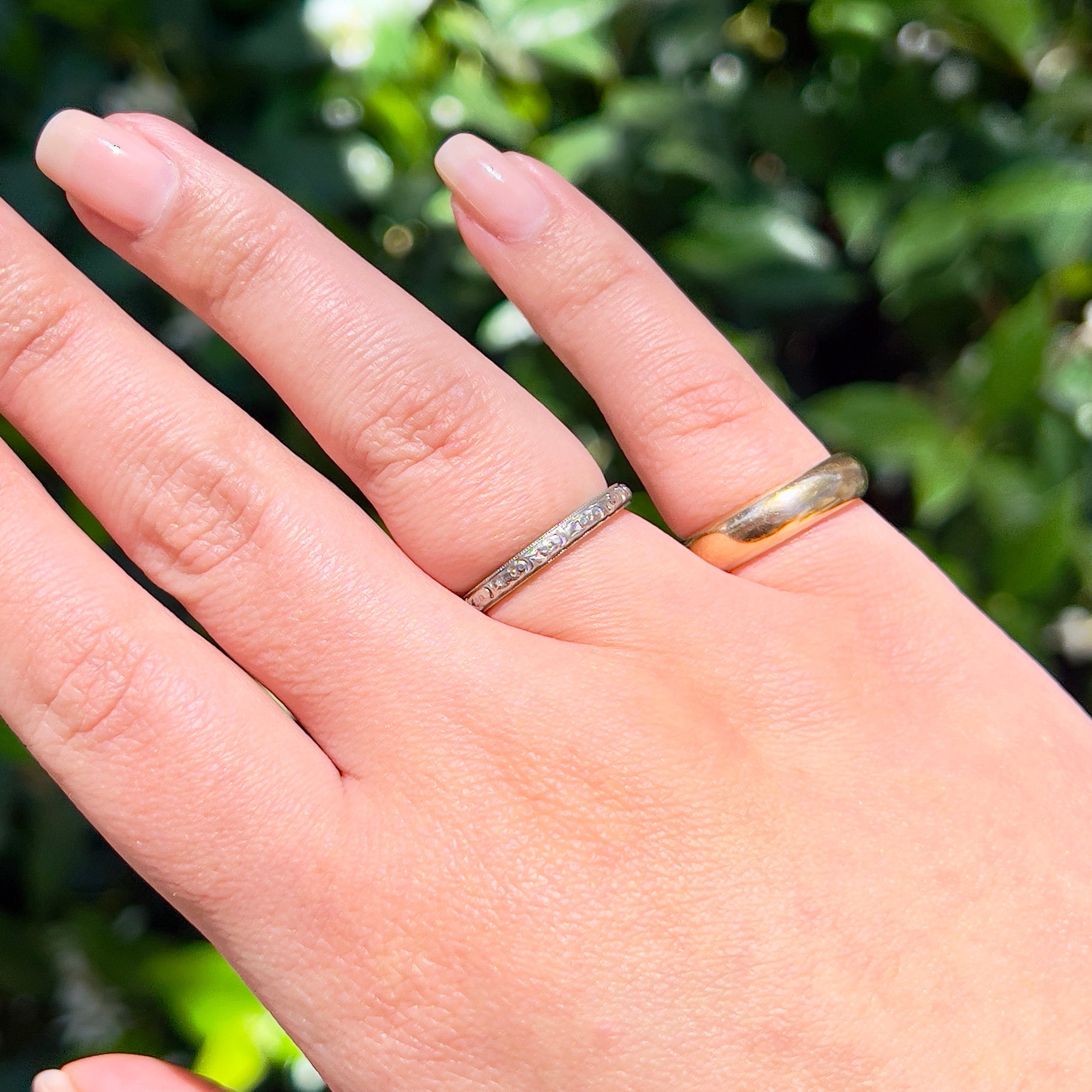 Two rings modeled on a had against an outdoor background.