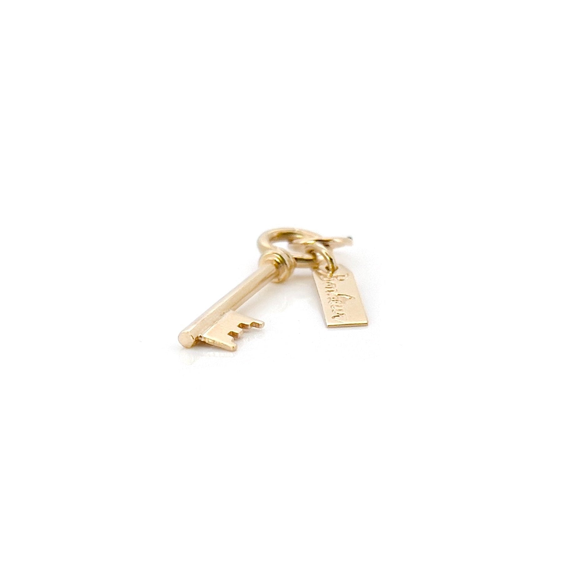 A gold key charm with the word 'bonheur' inscribed on a tag.
