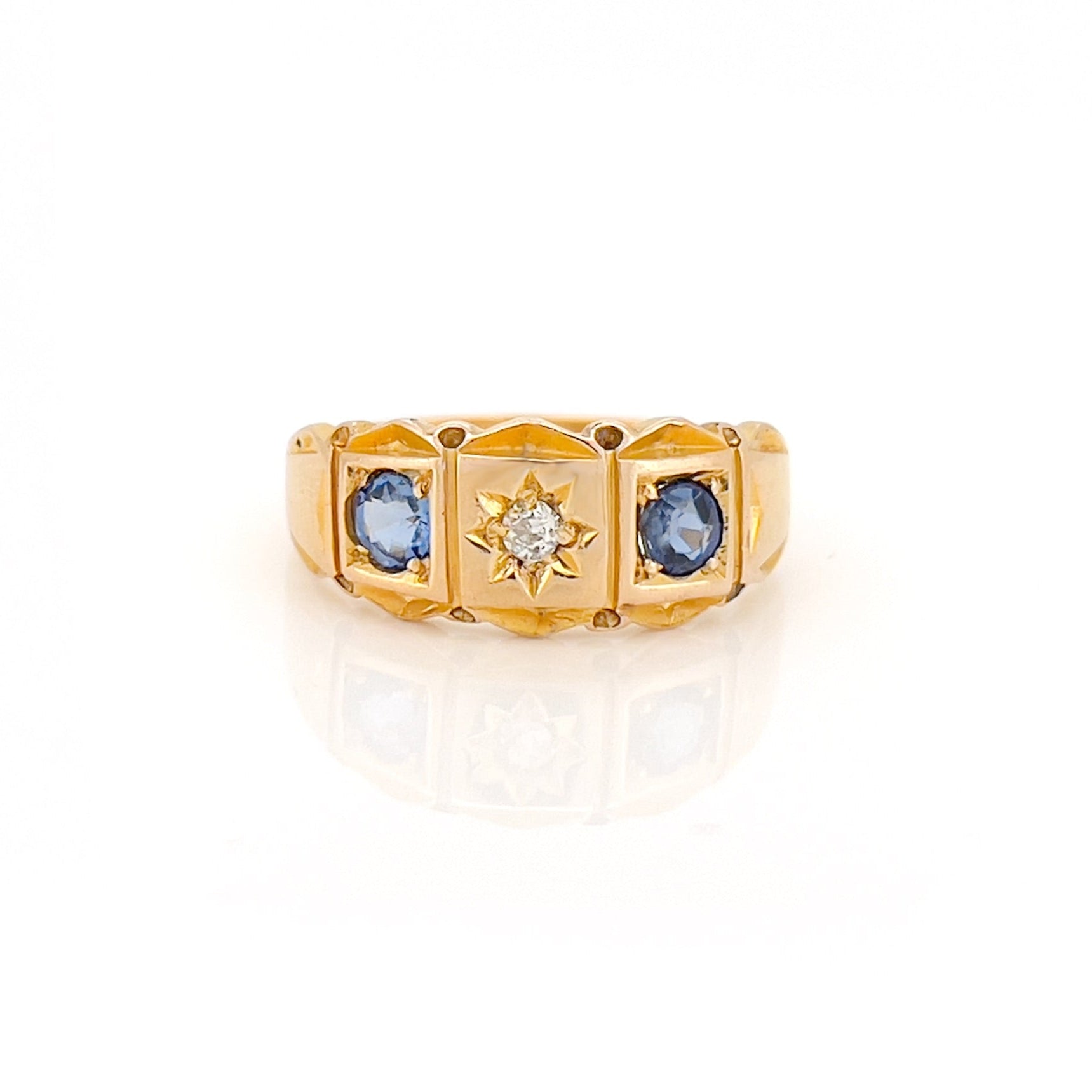 Gold ring with blue gemstones and a diamond on a white background