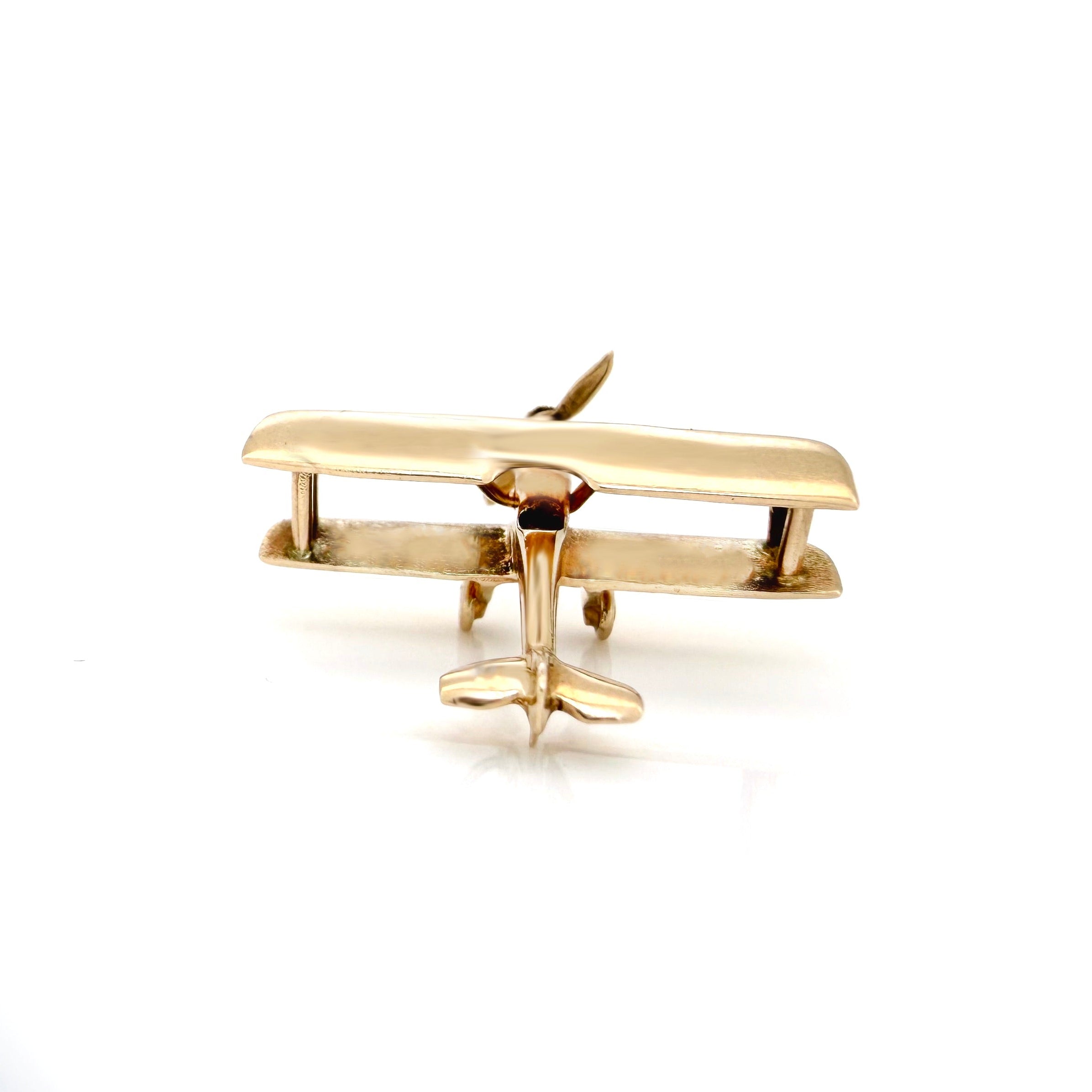 Gold airplane-shaped pendant on a white background