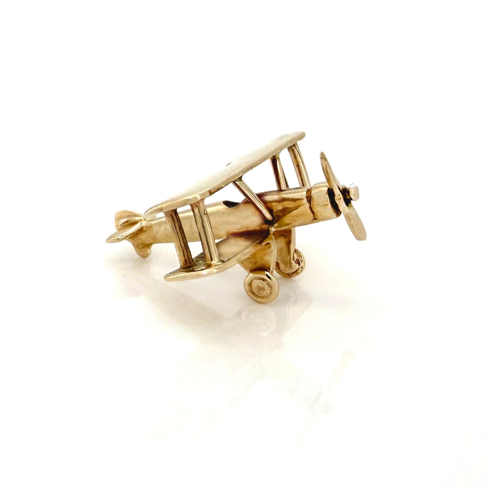 Gold airplane charm on a white background