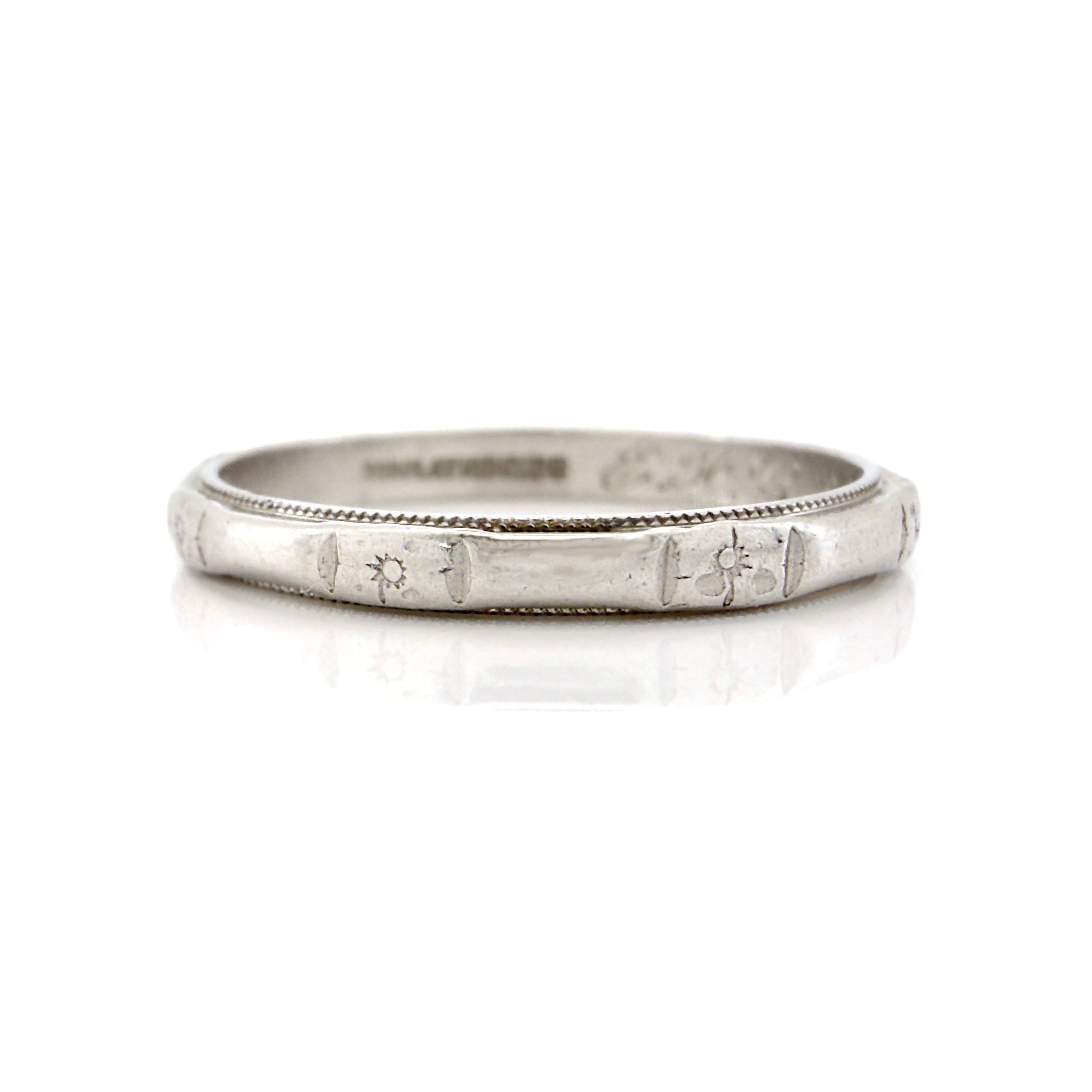 Silver ring with engraved details on a white background