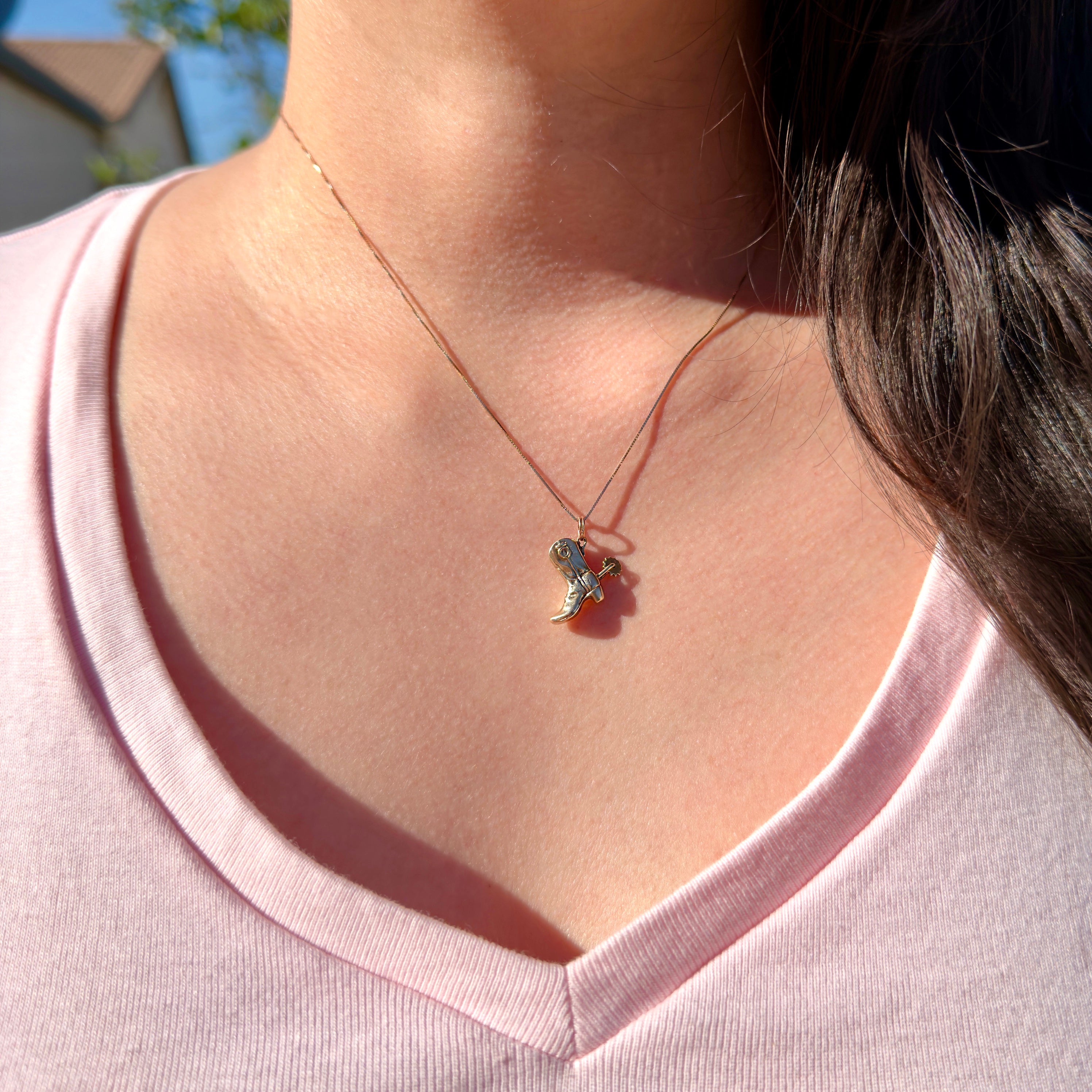 Necklace with a pendant worn by a person in a pink shirt outdoors