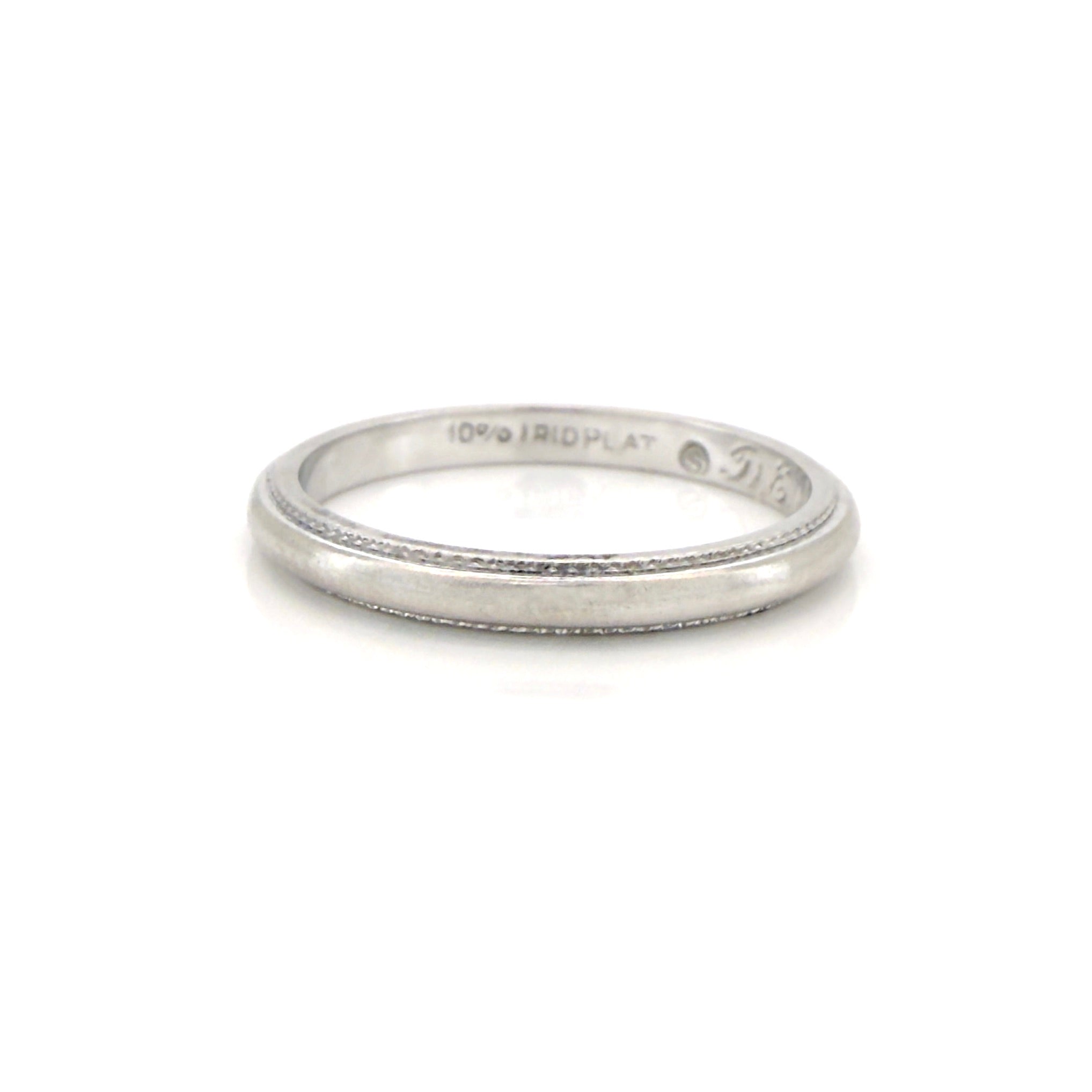 Vintage platinum ring with engraved text on a white background