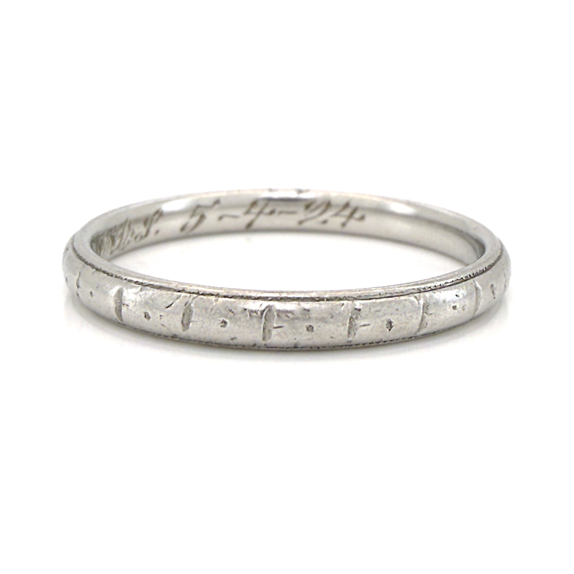 Antique platinum ring with engraved design on a white background