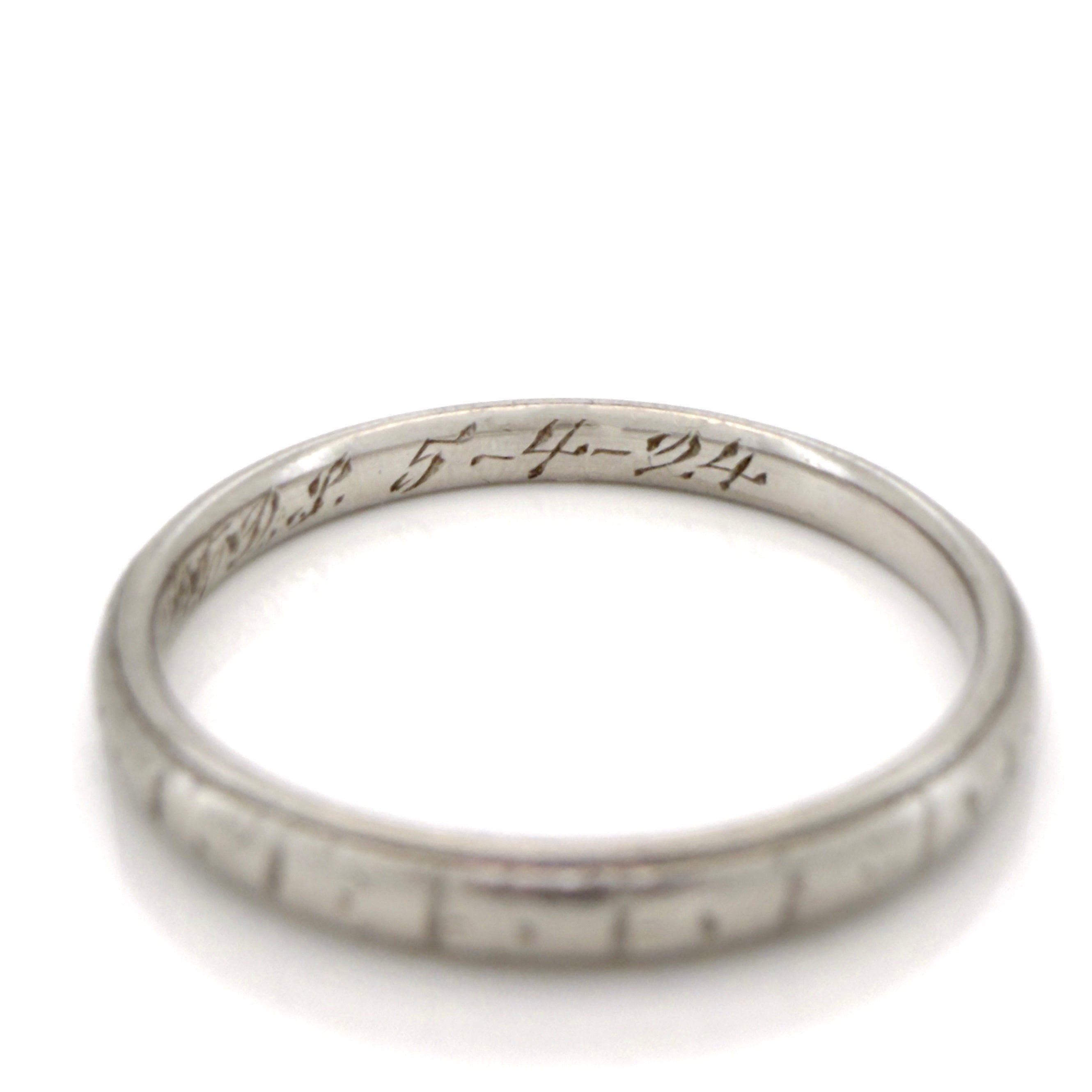 Antique platinum ring with engraved design on a white background