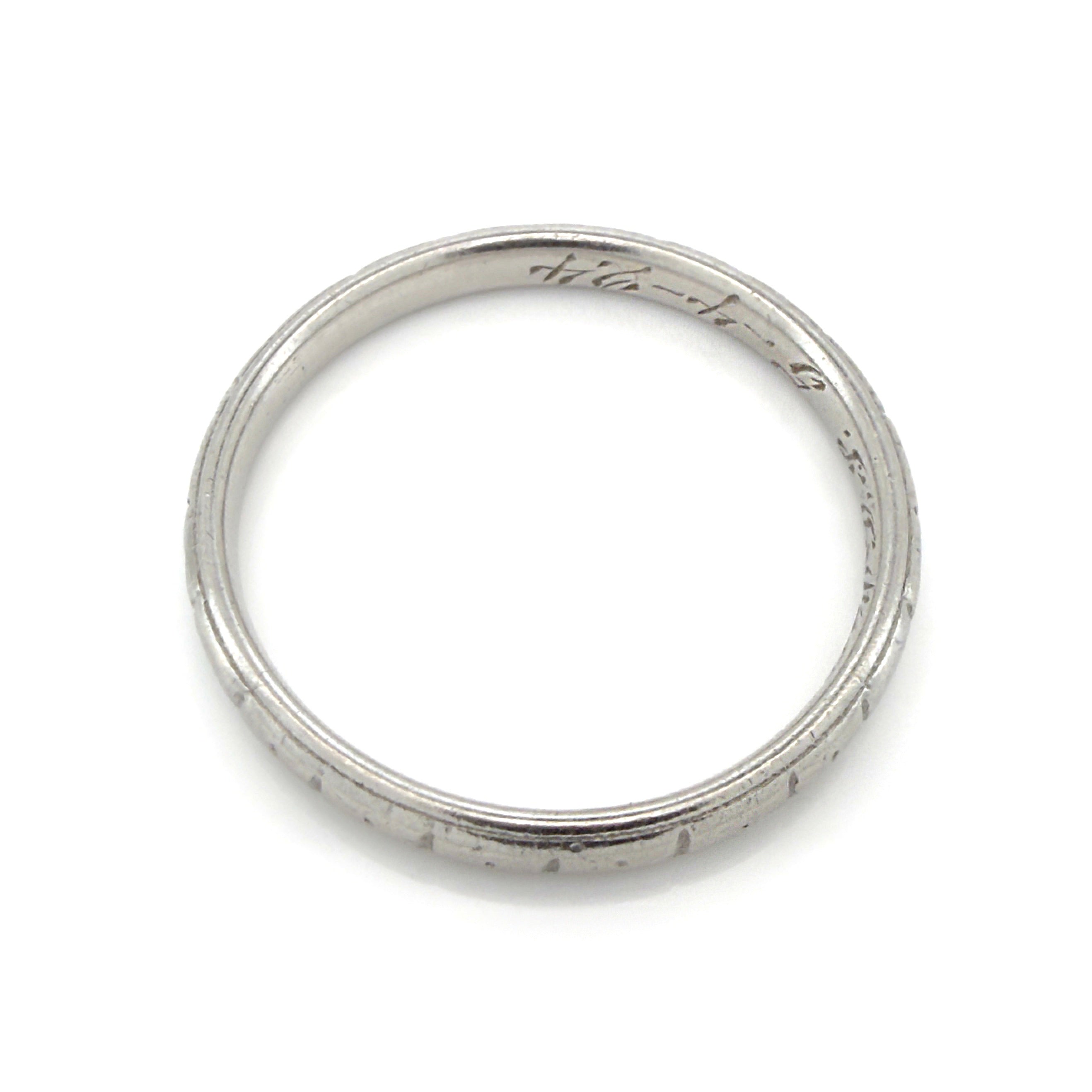 Antique platinum ring with engraved design on a white background