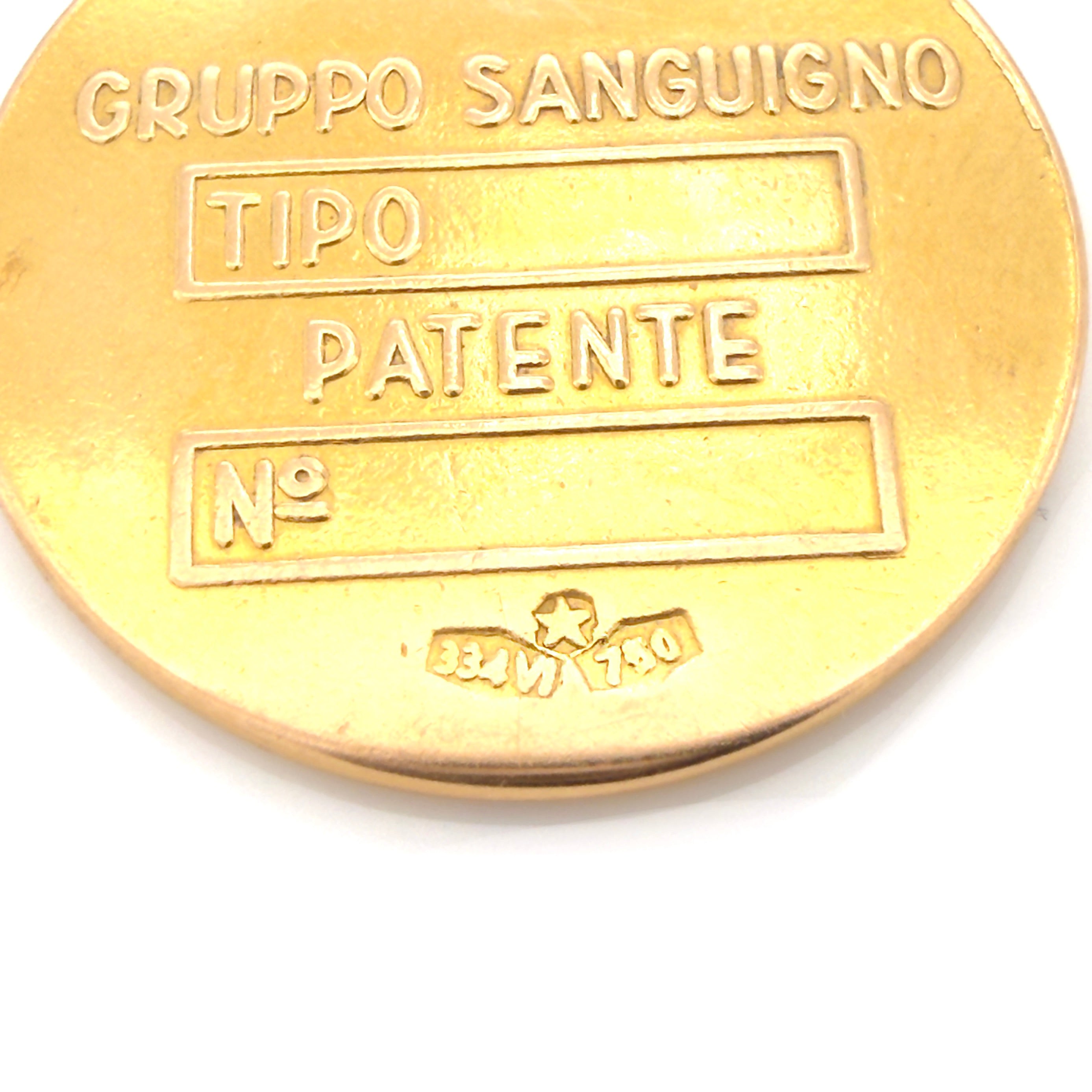 Vintage gold pendant with text 'GRUPPO SANGUIGNO', 'TIPO', 'PATENTE', and Italian hallmarks on a white background