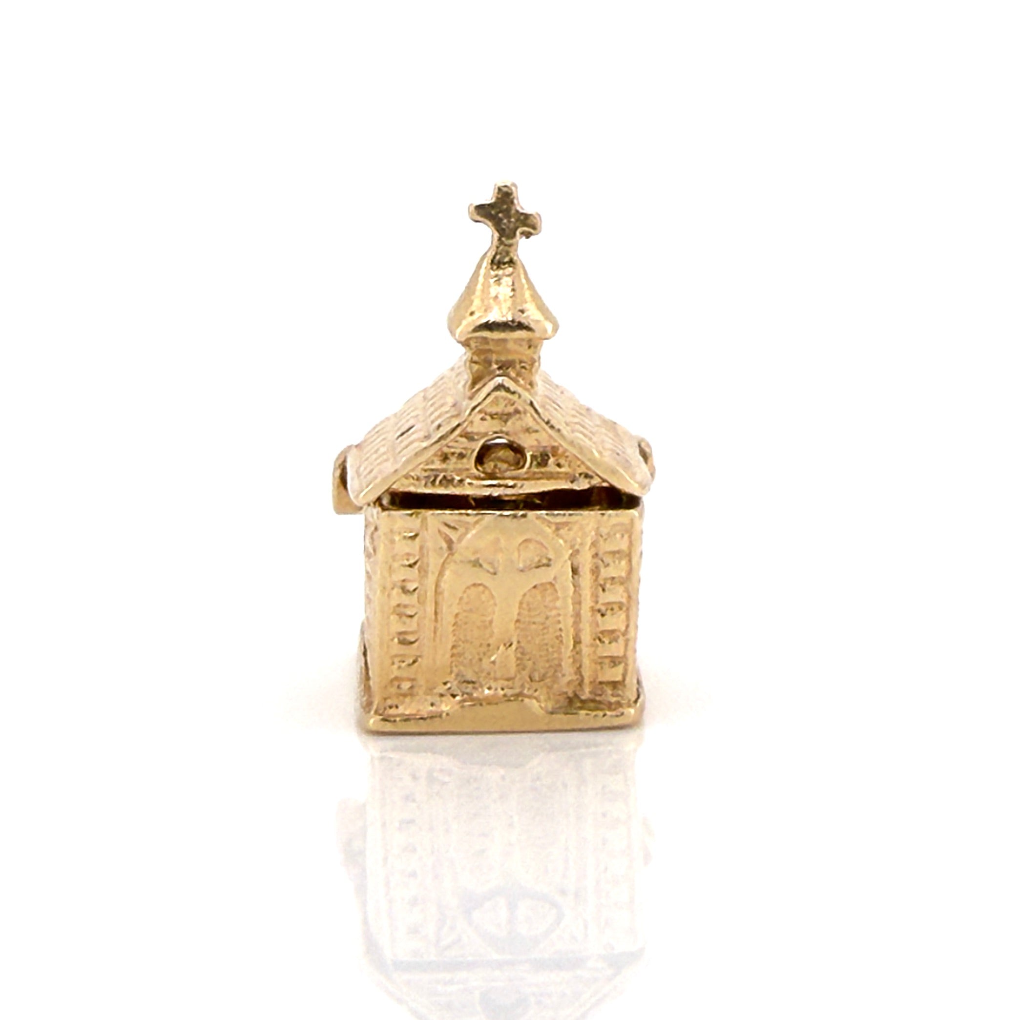 Vintage gold charm shaped like a small church on a white background