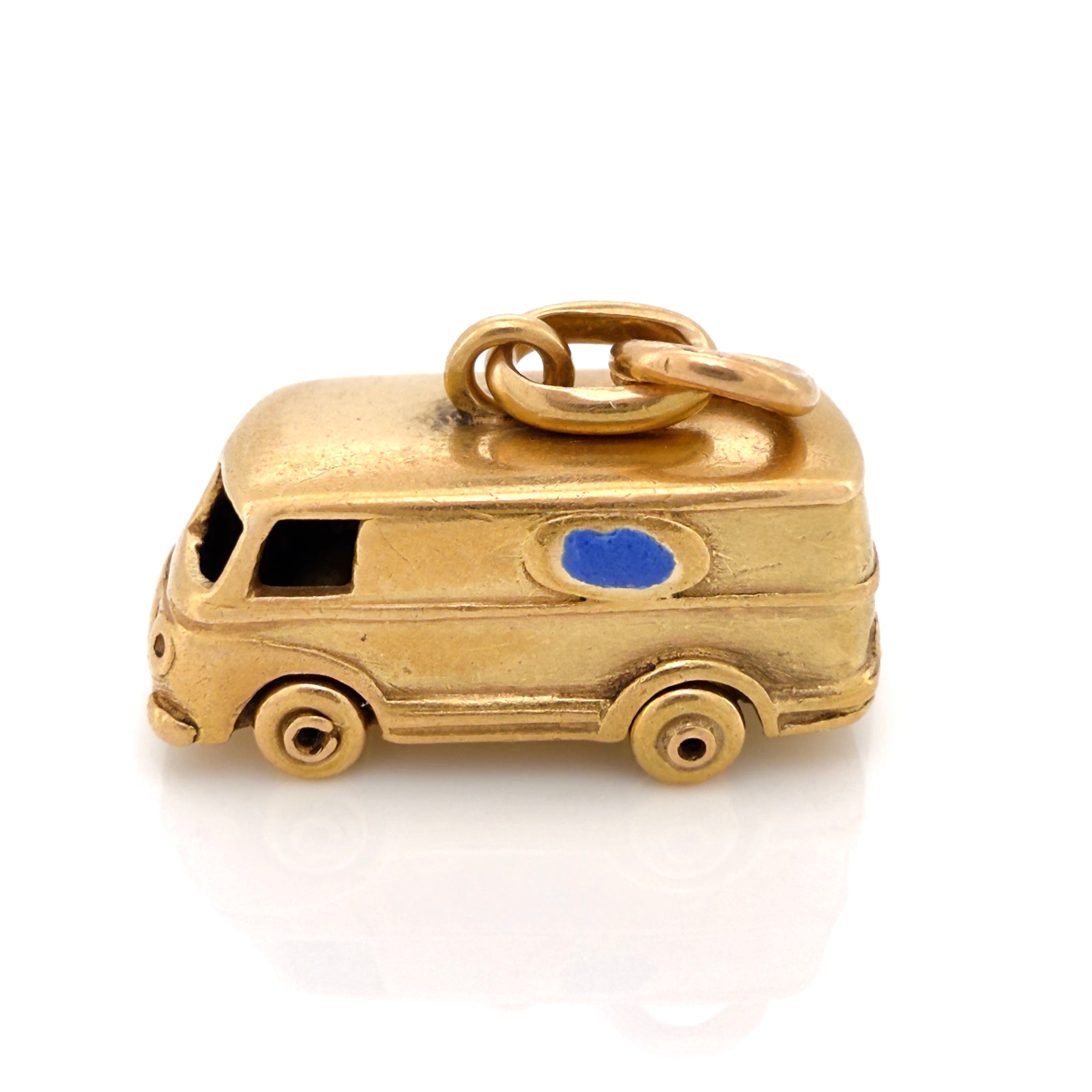 Vintage gold microbus charm with a light blue enamel window on a white background