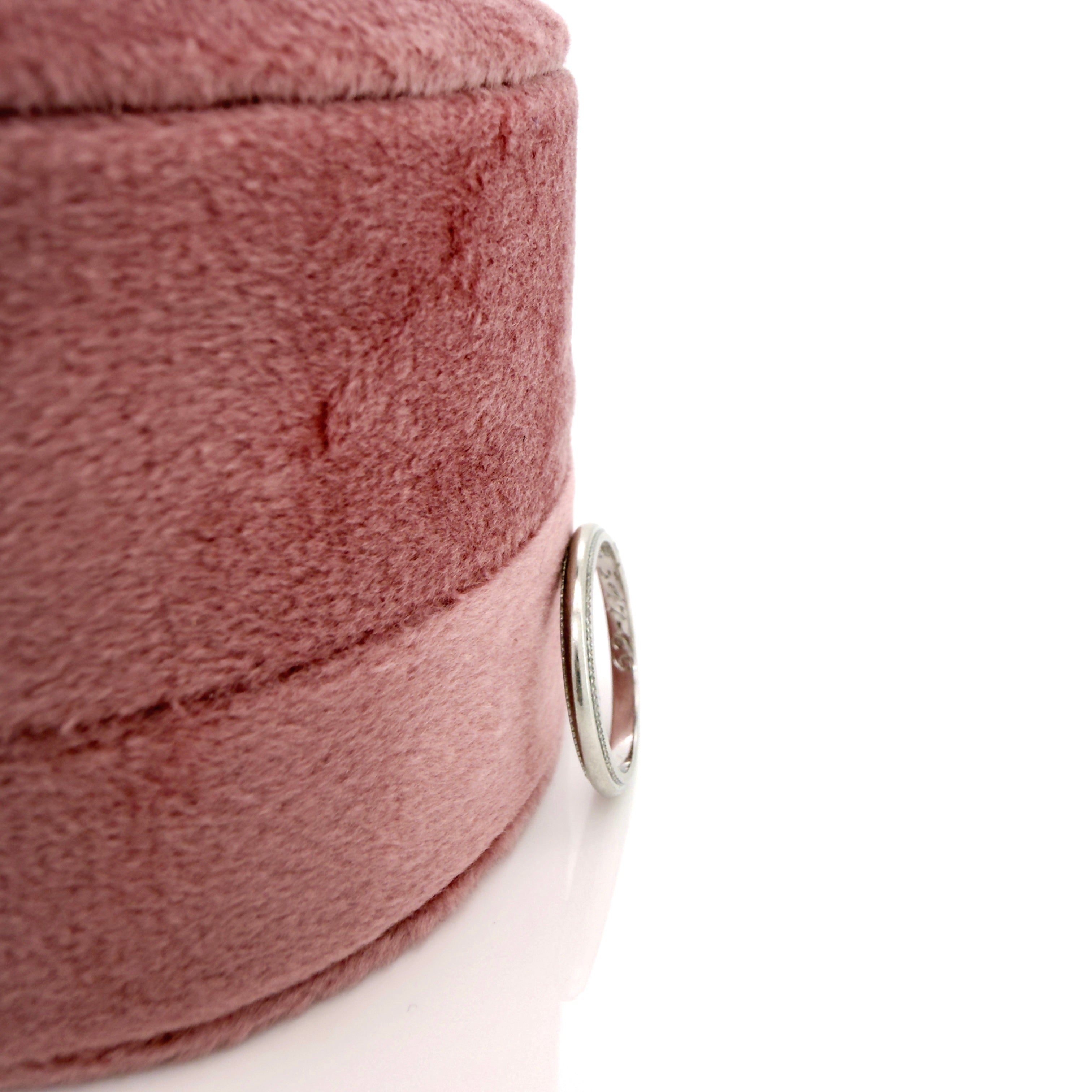 Close-up of a pink jewelry box with a vintage platinum ring on a white background