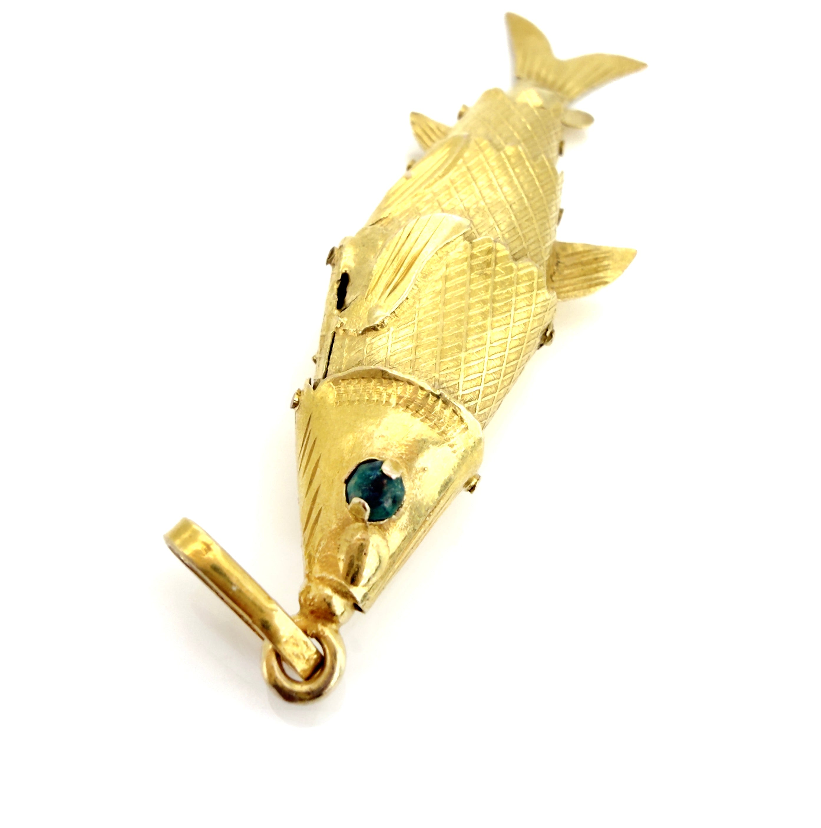 Gold fish-shaped brooch with a green gemstone on a white background