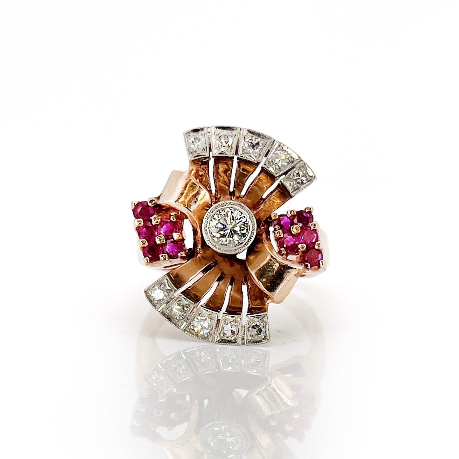Elegant retro rose gold and palladium ring with diamonds and rubies against a white background. 