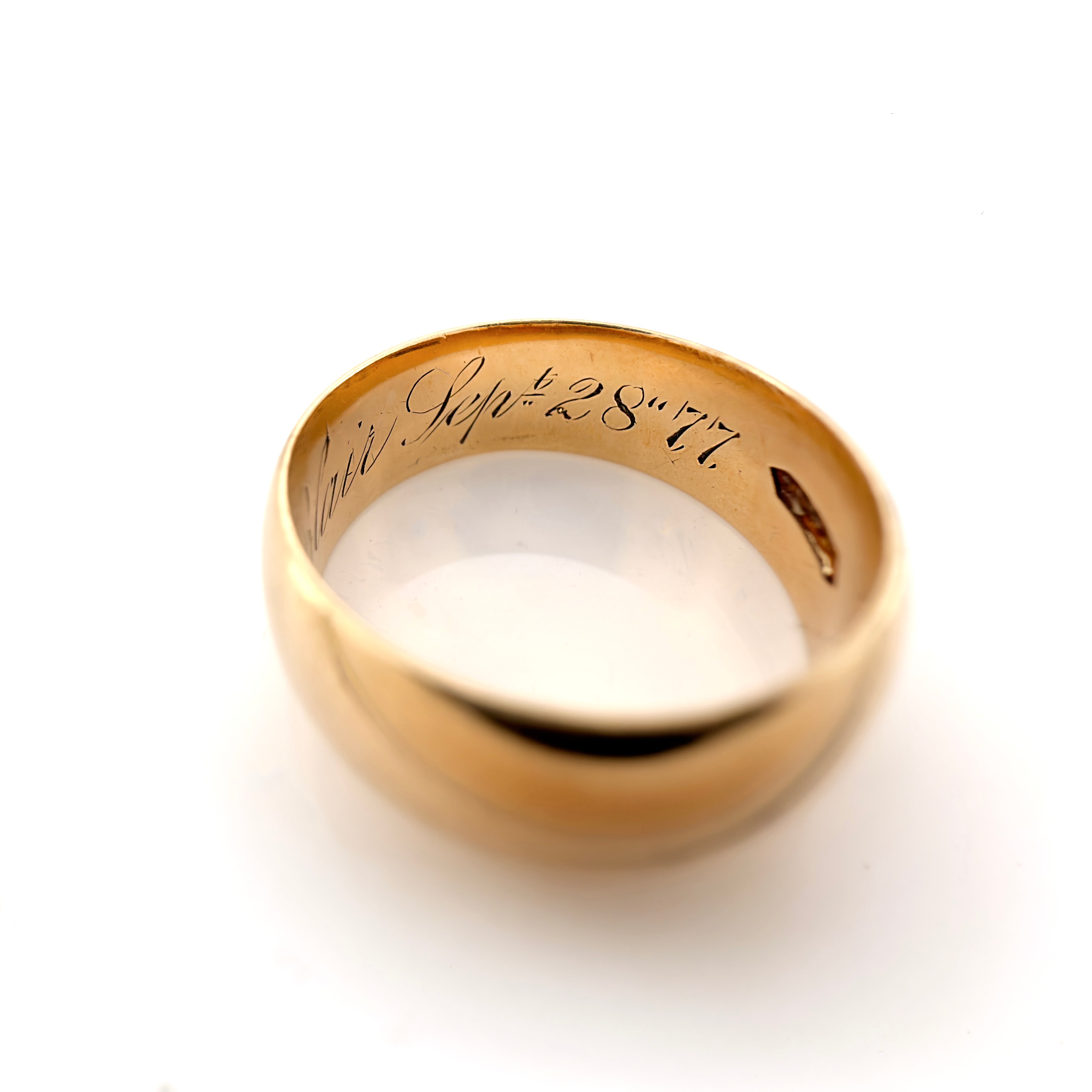 A polished yellow gold ring photographed on a clean white background. The inside of the band is engraved with the date 'Sept. 28, 77.'