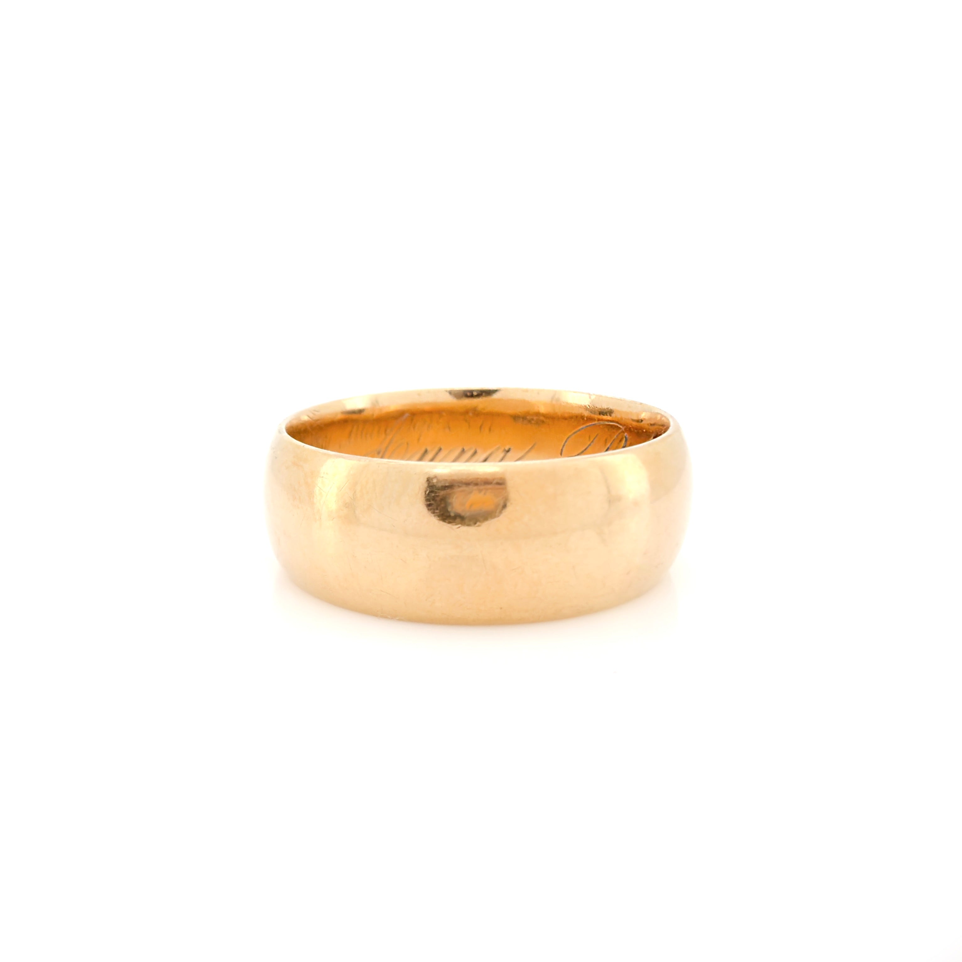 A Victorian gold band with a patina and inscription in front of a white background.
