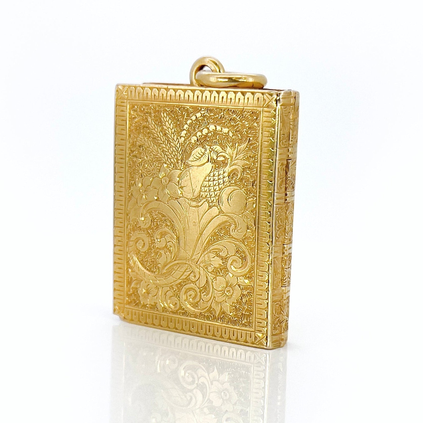 Gold Victorian book locket with intricate design against a white background