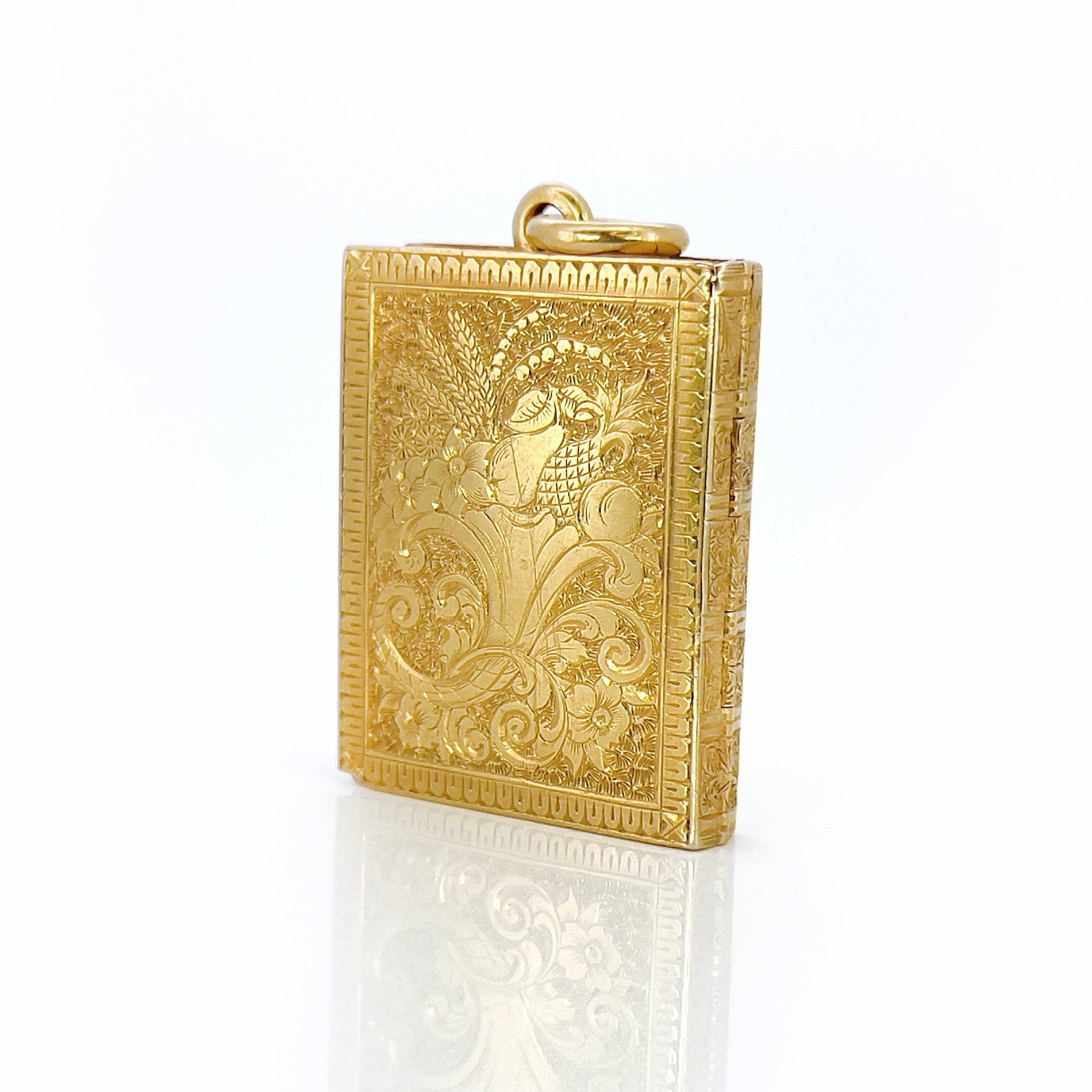 Gold Victorian book locket with intricate design against a white background