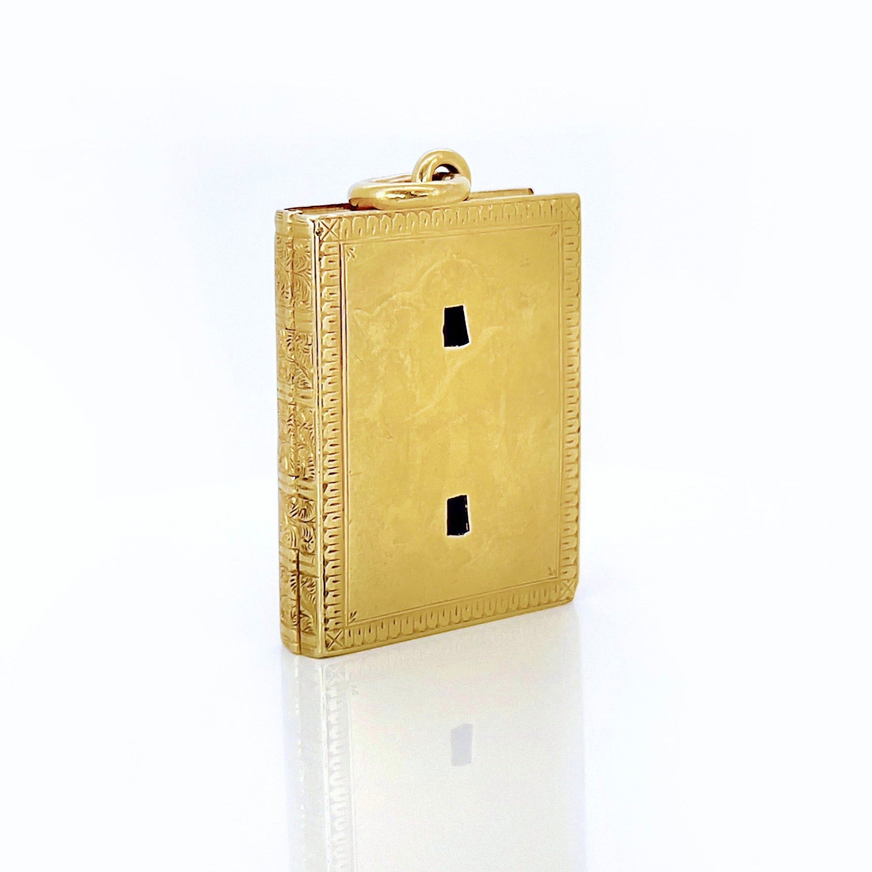 Gold Victorian book locket with intricate design against a white background