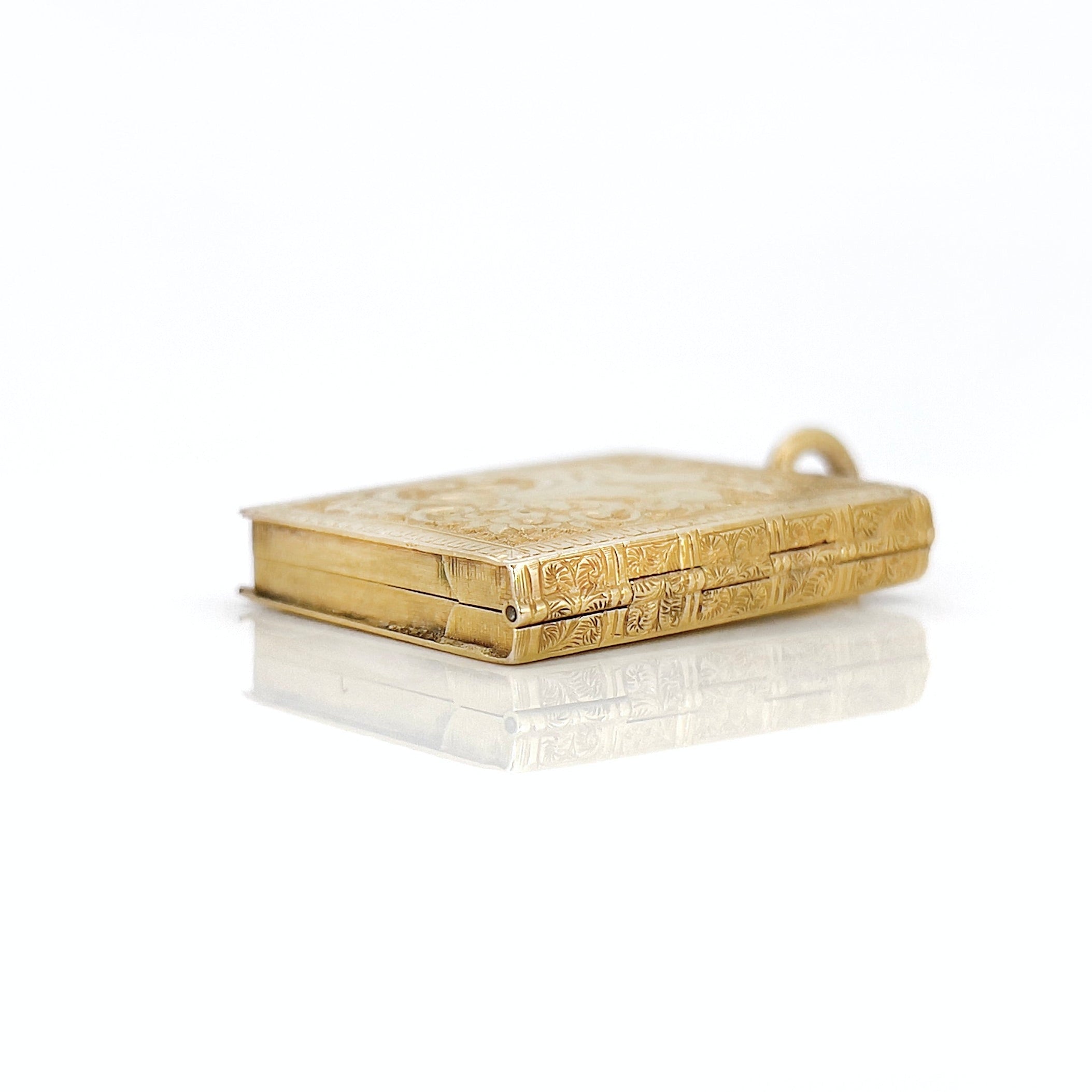 Gold Victorian book locket with intricate design against a white background