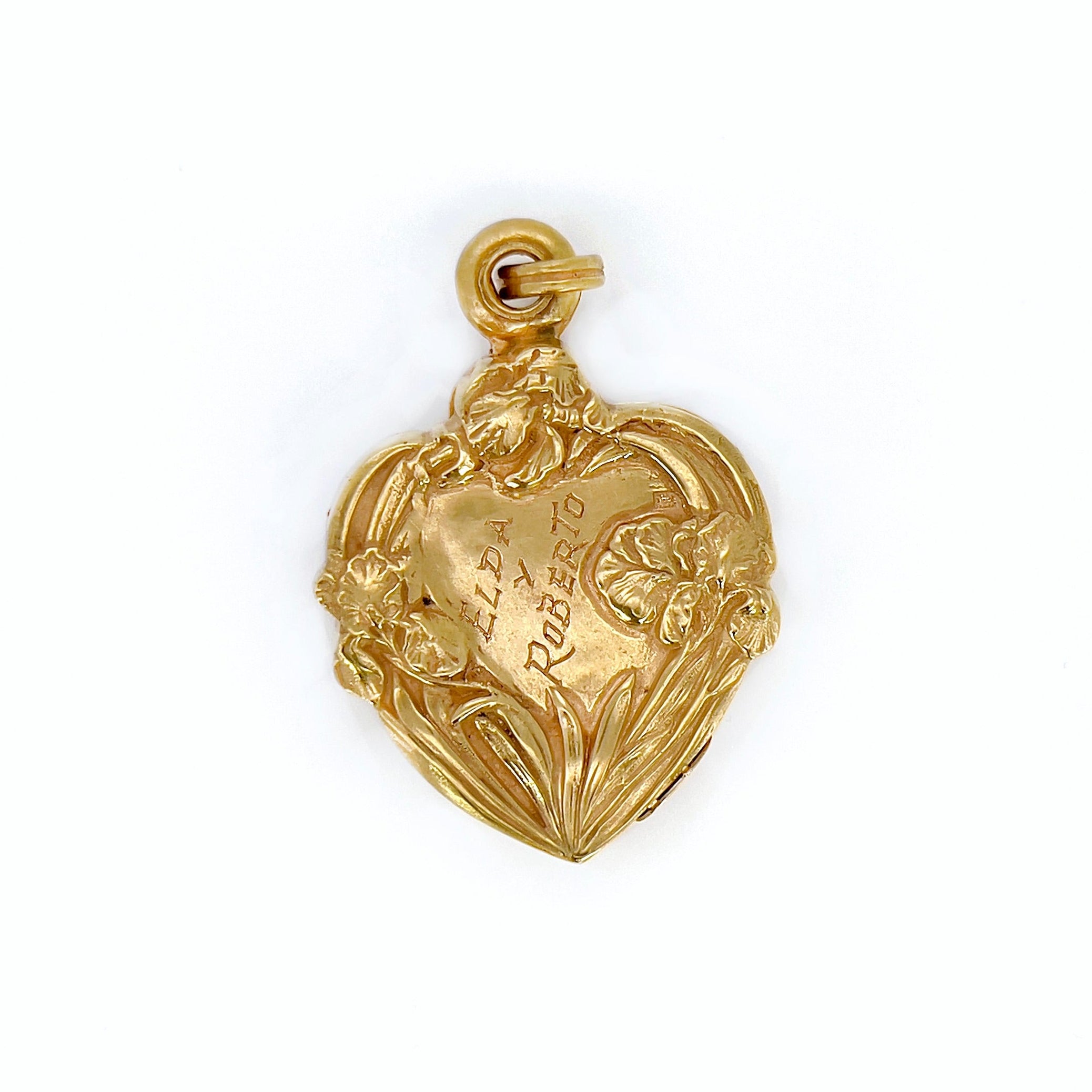 An Art Nouveau heart-shaped locket with gold detailing, featuring  flowers and an engraving, on a white background. 