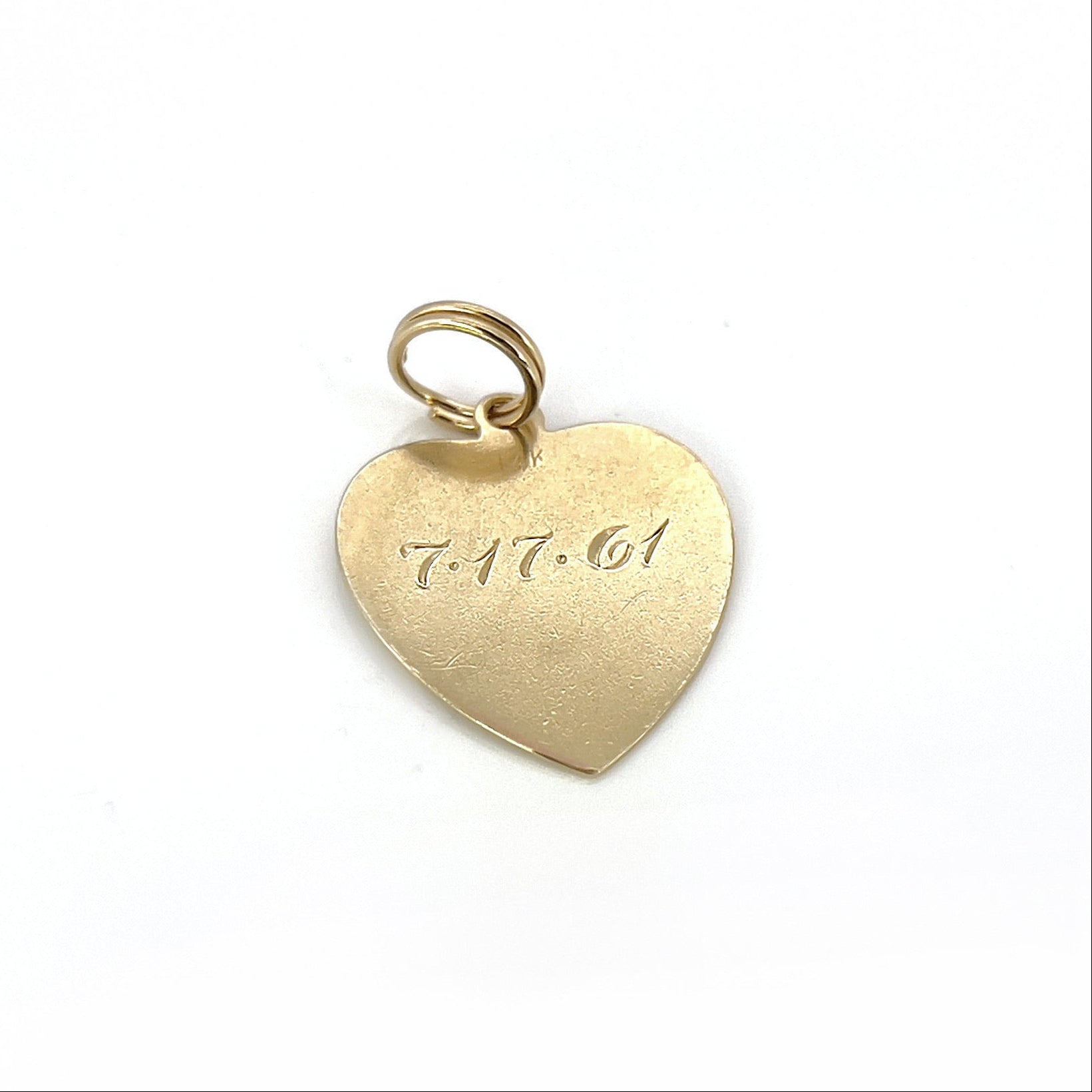 A vintage gold heart-shaped charm with the inscription 'Susan Marie' and a date '7-17-61' engraved on it.
