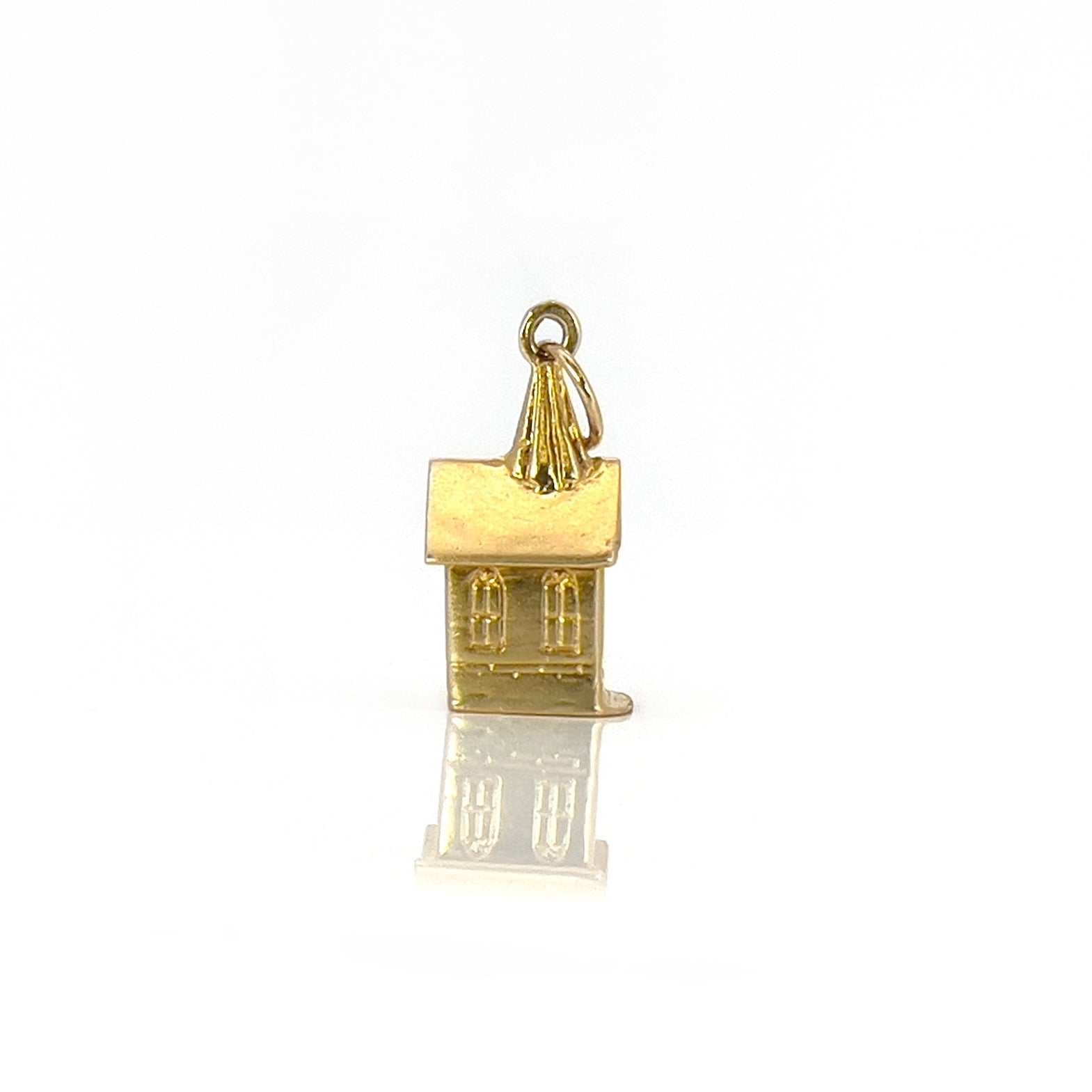 A vintage 14K yellow gold charm shaped like a chapel with a stanhope viewer.