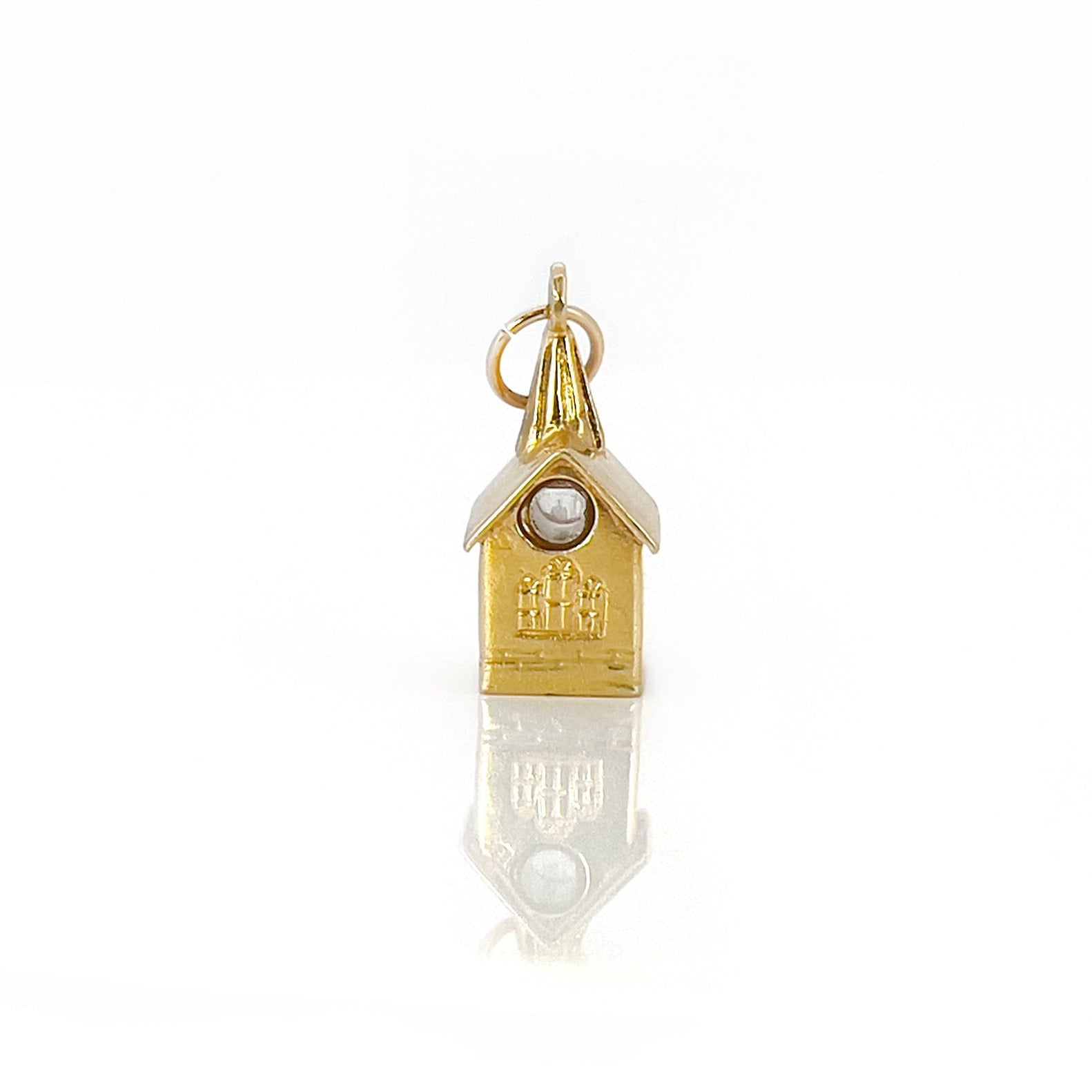 A vintage 14K yellow gold charm shaped like a chapel with a stanhope viewer.