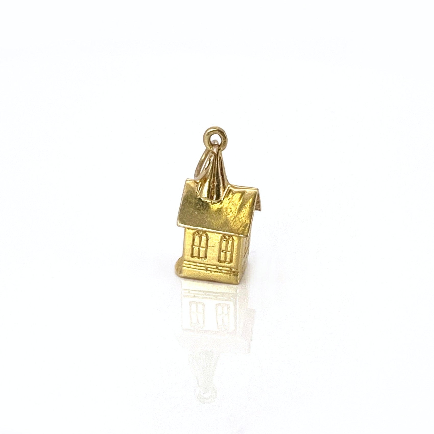 A vintage 14K yellow gold charm shaped like a chapel with a stanhope viewer.