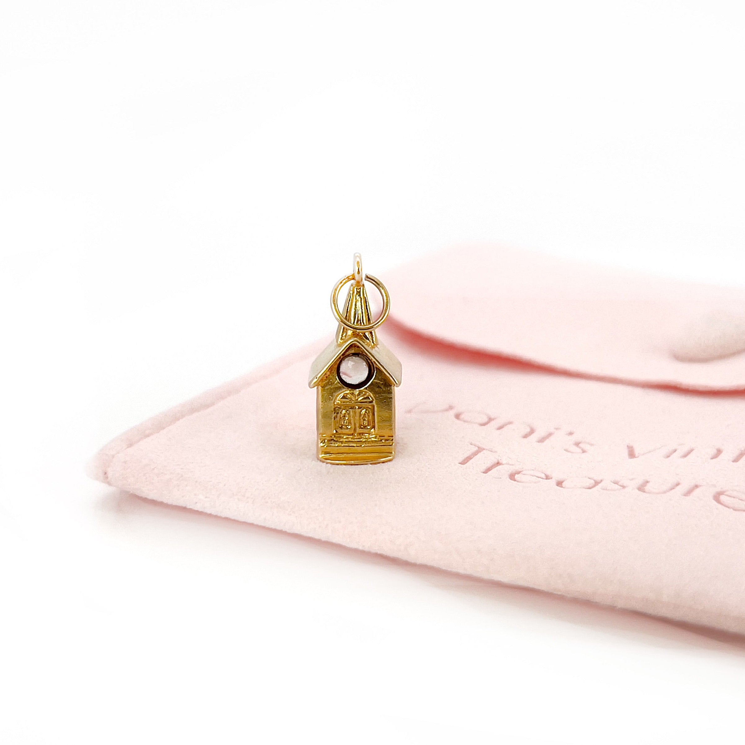 A vintage 14K yellow gold charm shaped like a chapel with a stanhope viewer.