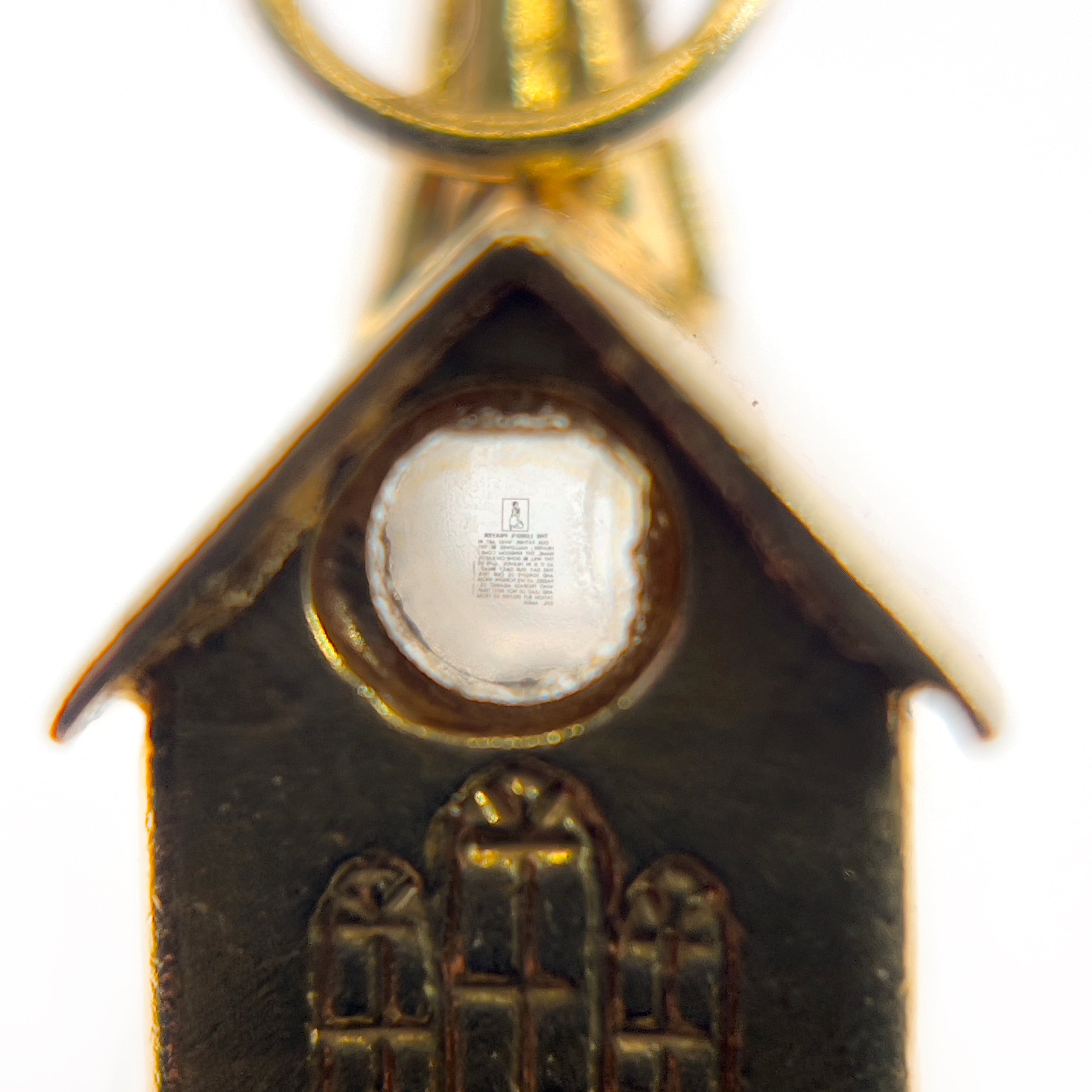 A close up of a vintage 14K yellow gold charm shaped like a chapel with a stanhope viewer.