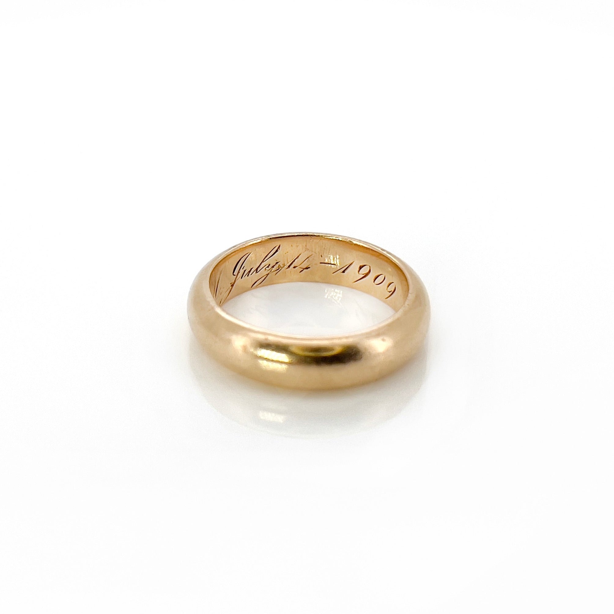 An antique gold band with an inscription, displayed against a white background.