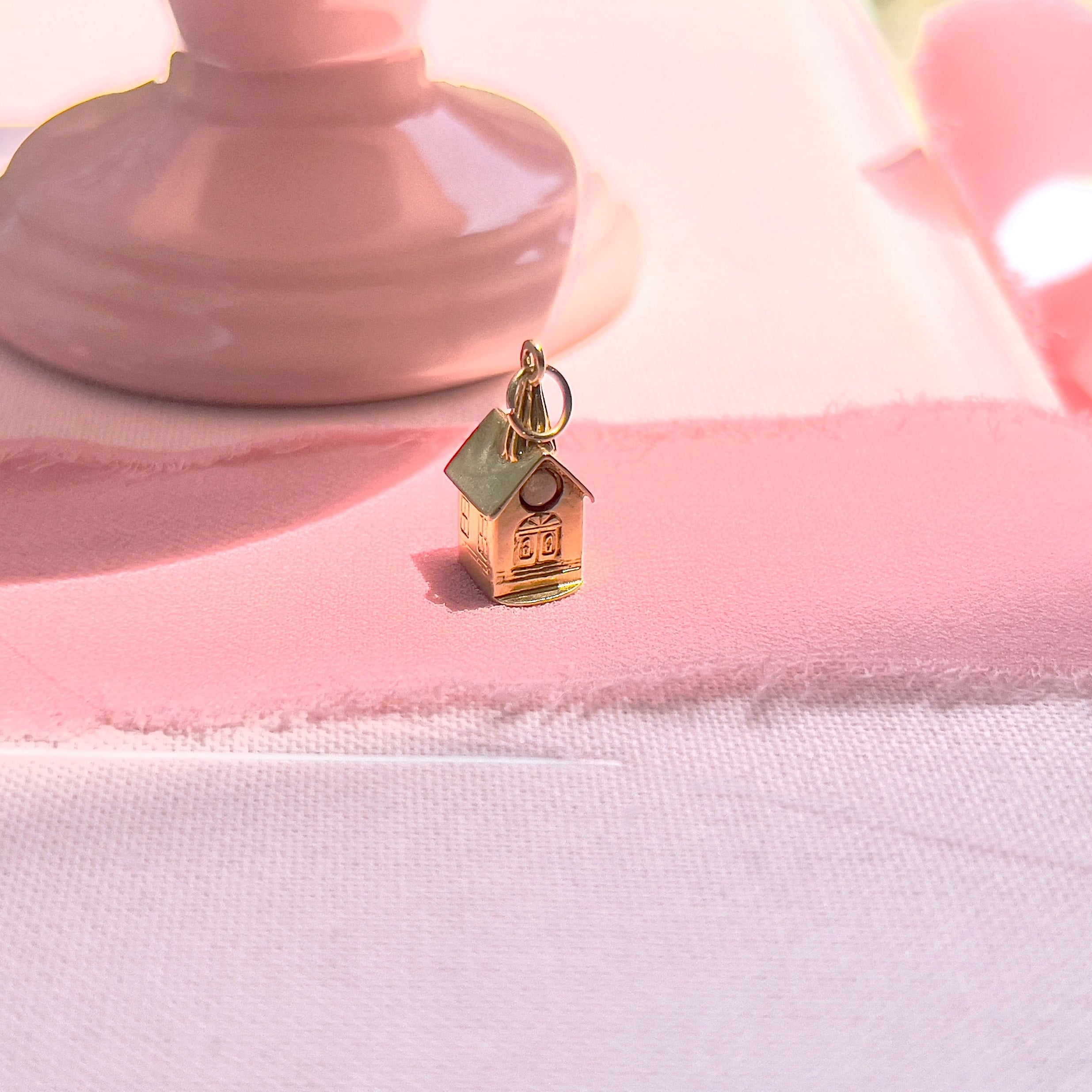 A vintage 14K yellow gold charm shaped like a chapel with a stanhope viewer.