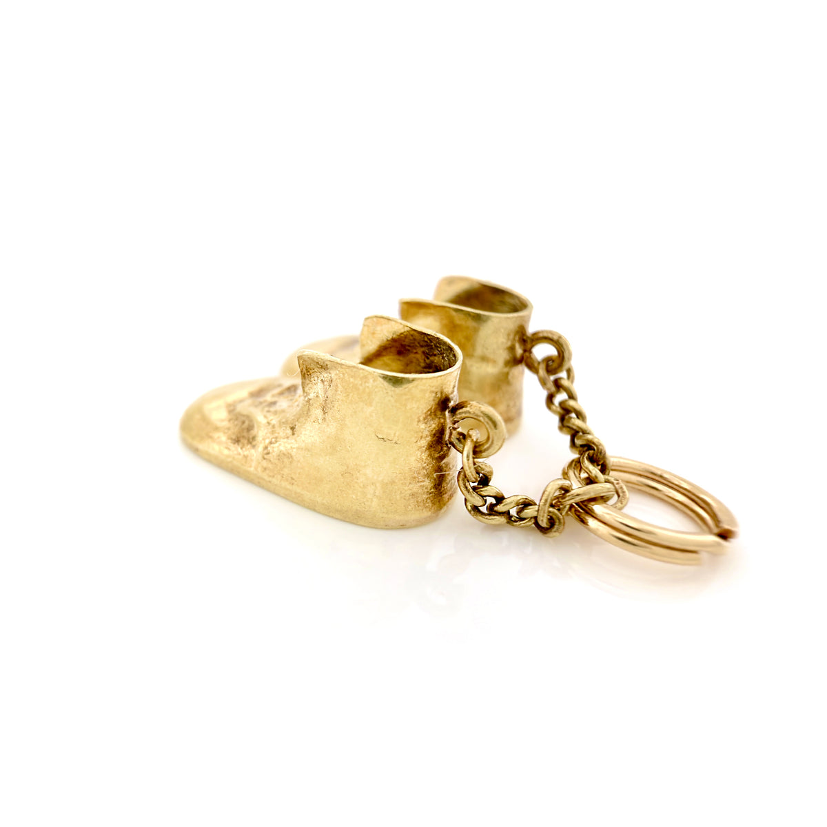 A gold baby boot keychain with a textured boot charm, a short chain, and a split key ring, shown on a clean white background.