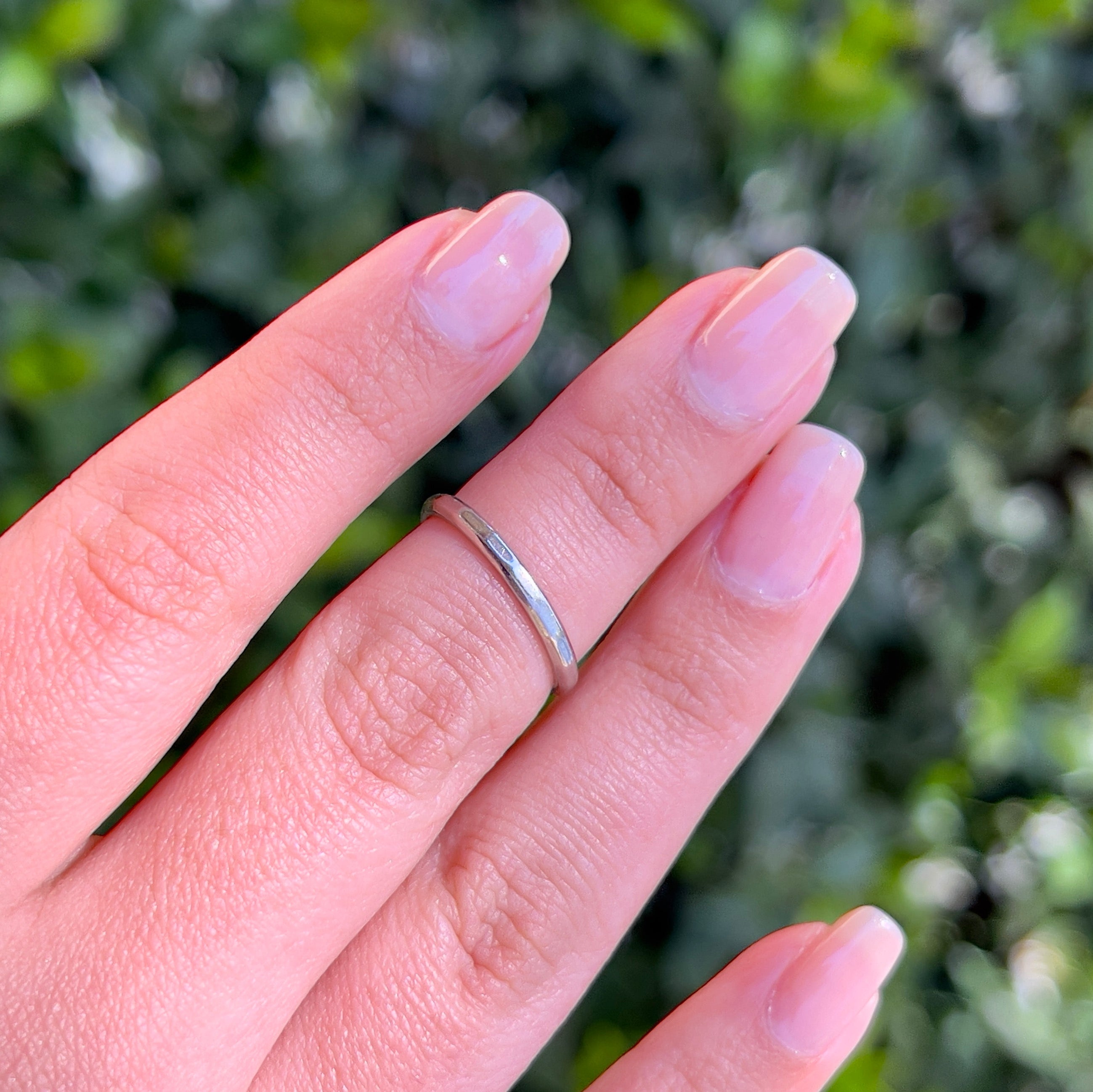 A platinum vintage ring modeled on a hand against a blurred background.