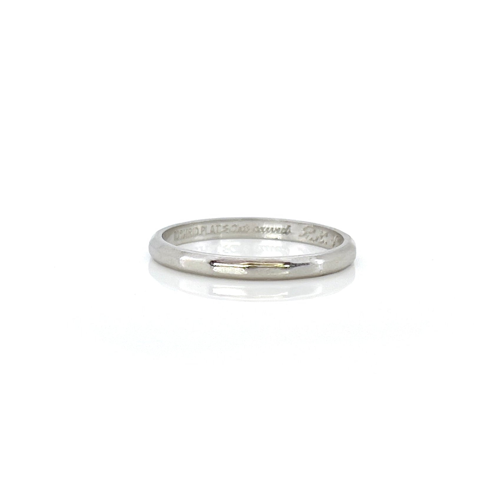 A vintage platinum ring with art carved design, showing visible wear and an inscription on the inside.