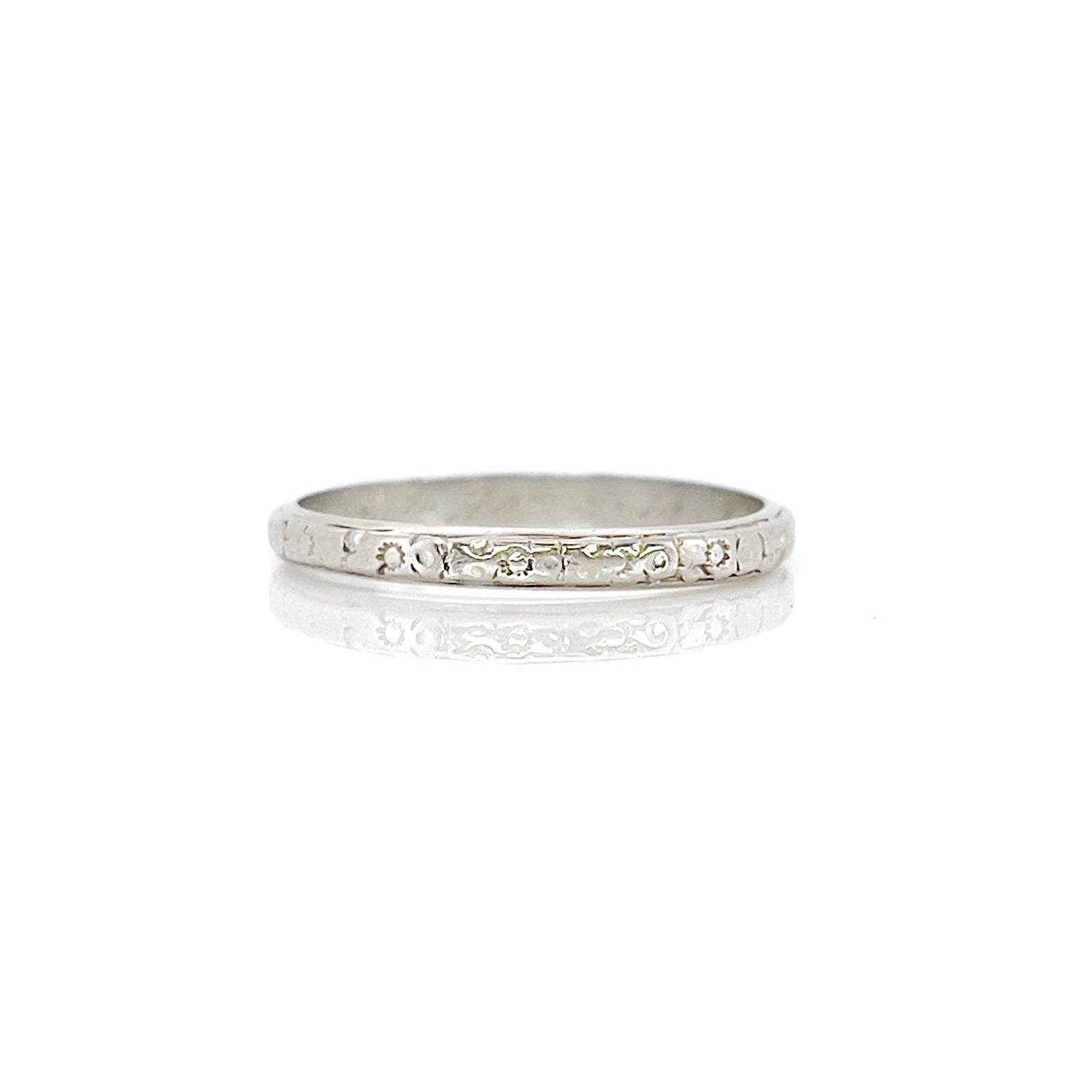 A vintage 14K white gold wedding band with an intricate floral design and personalized engraving inside.