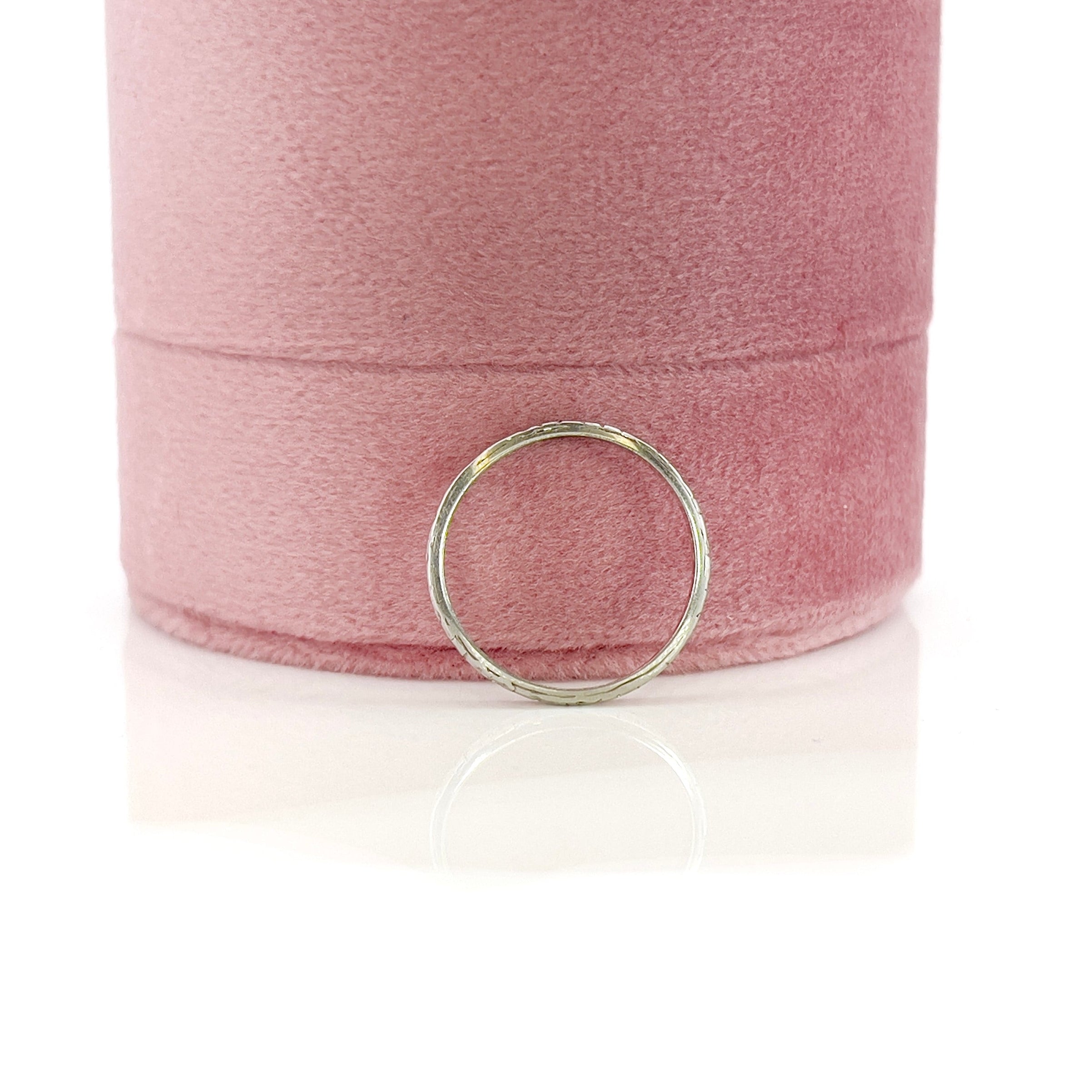 A vintage 14K white gold wedding band with an intricate floral design and personalized engraving inside.