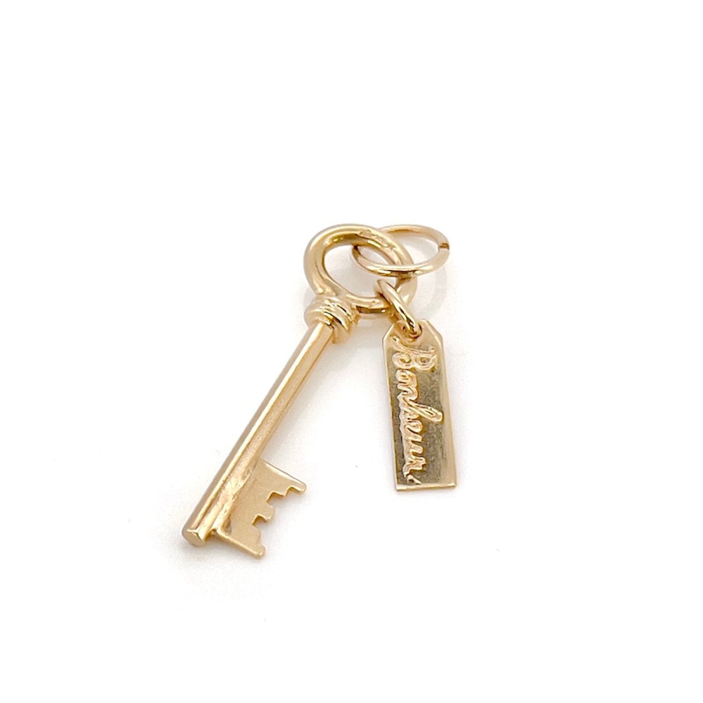 A gold key charm with the word 'bonheur' inscribed on a tag.