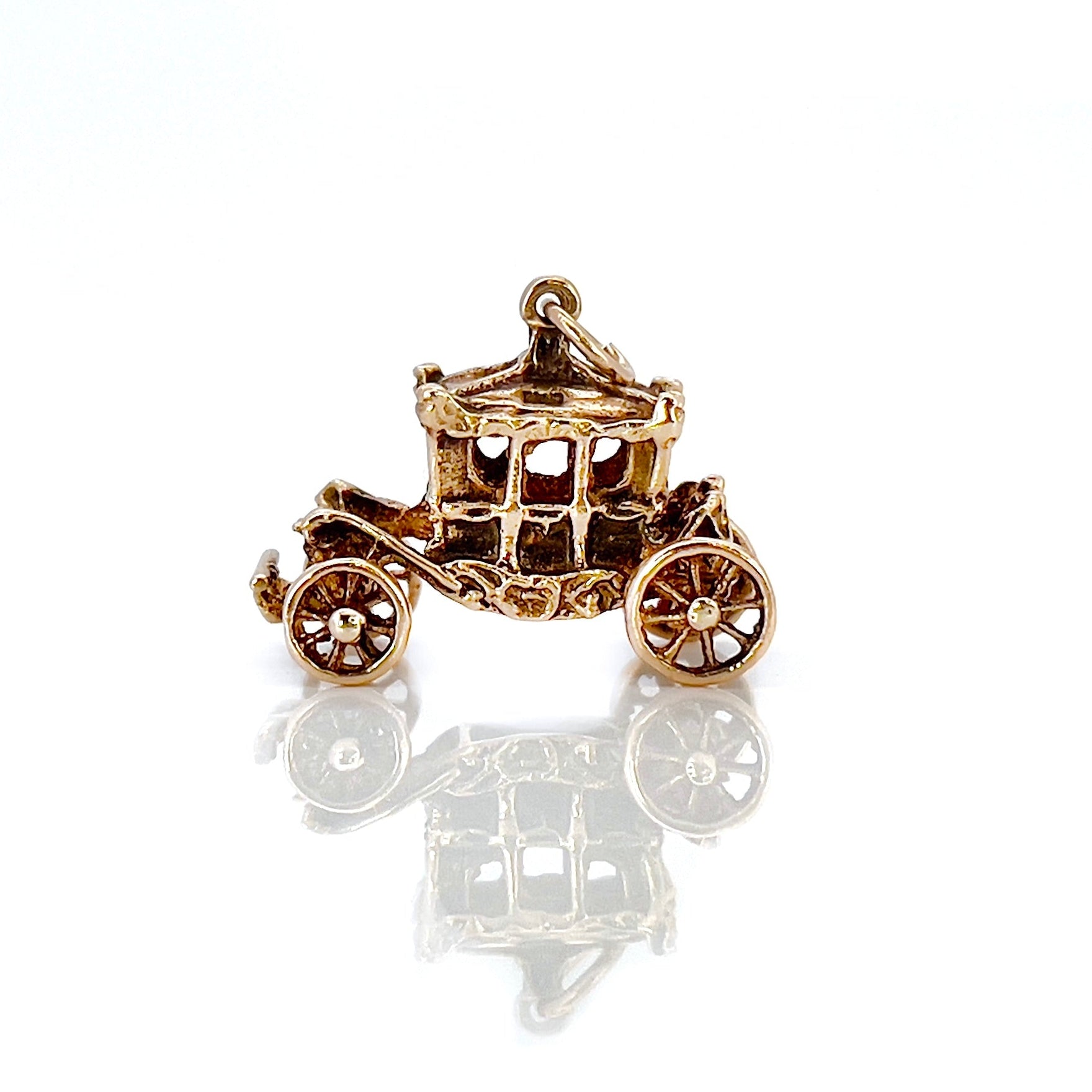 A vintage 9KT gold charm shaped like a Cinderella carriage with moving wheels, crafted in 1962.