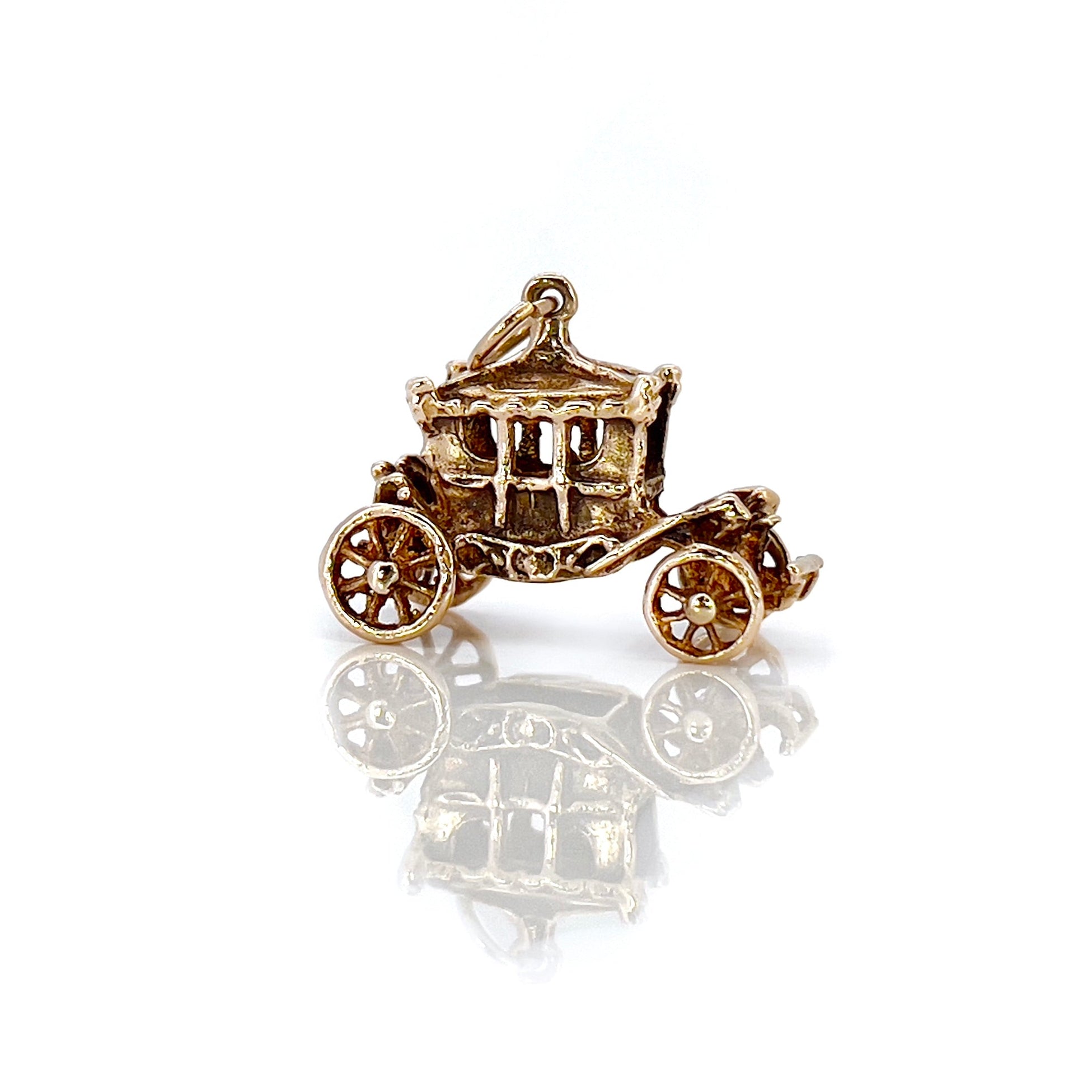 A vintage 9KT gold charm shaped like a Cinderella carriage with moving wheels, crafted in 1962.