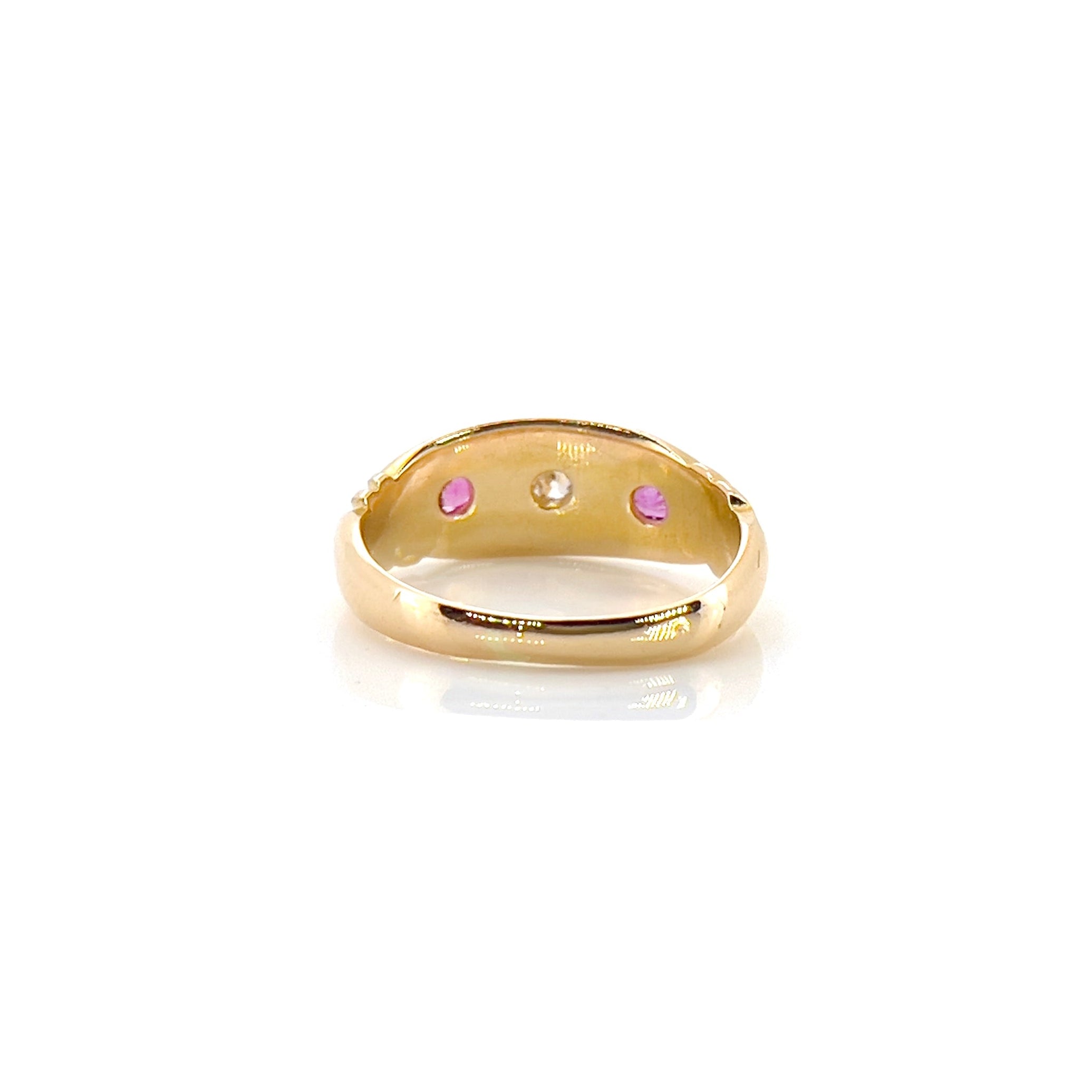 The back of a Victorian Old Mine Cut Diamond Starburst Ring with a central diamond surrounded by two rubies, set in 18K gold with scroll work on its shoulders