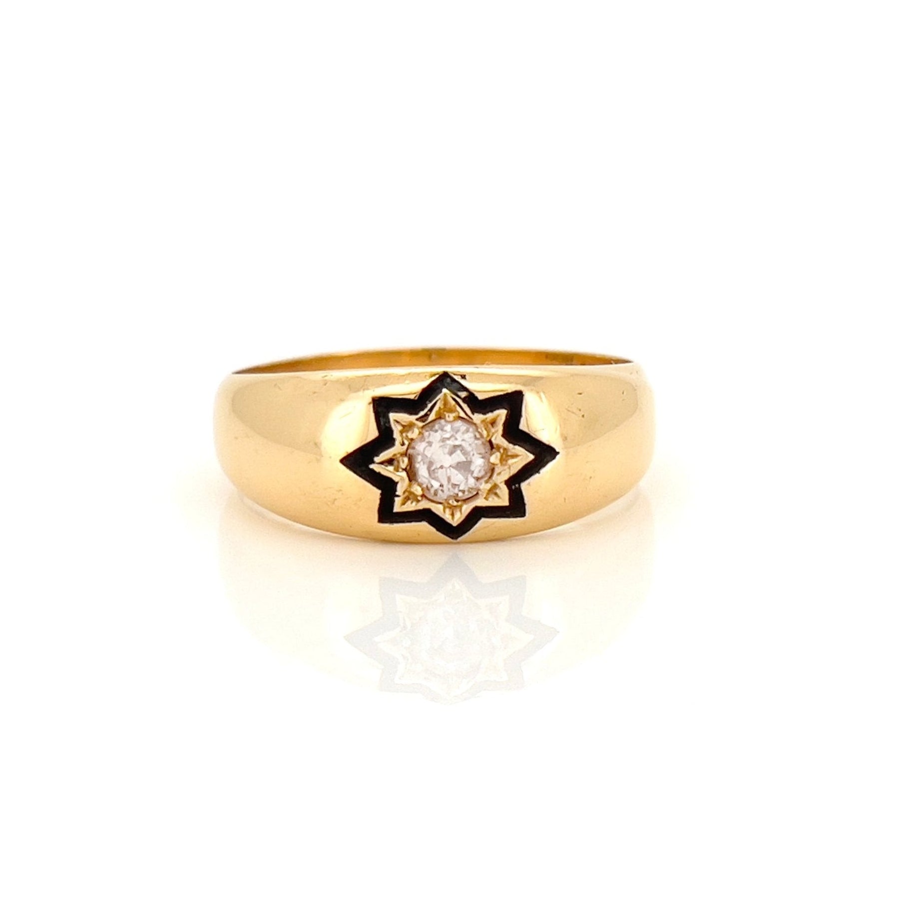 A Victorian old European cut diamond starburst ring with a cognac color diamond in the center, surrounded by enamel detailing on a yellow gold band.