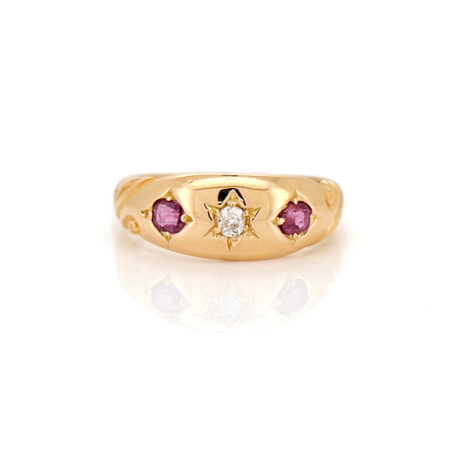 A Victorian Old Mine Cut Diamond Starburst Ring with a central diamond surrounded by two rubies, set in 18K gold.